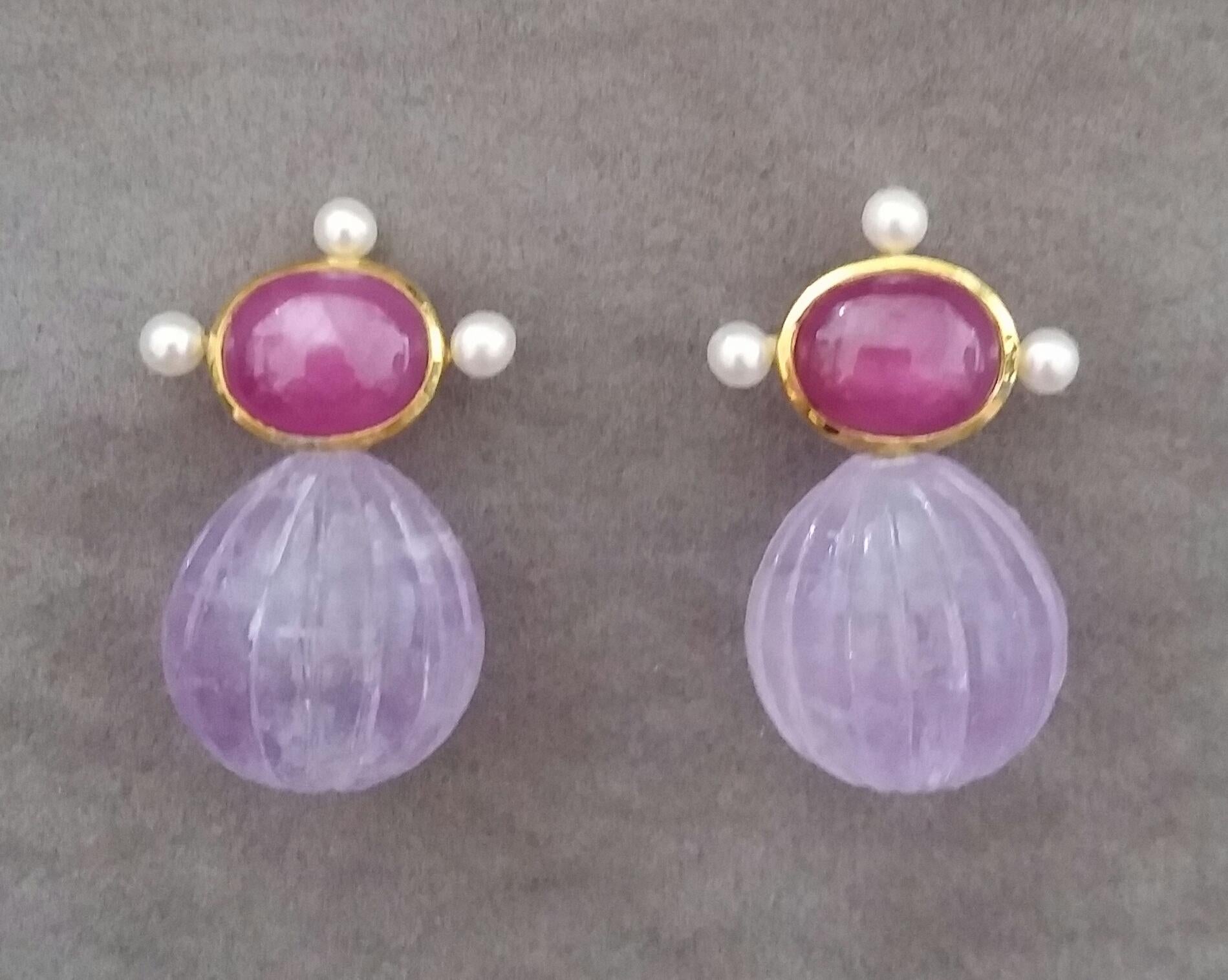 These elegant and handmade earrings have 2 Oval  Natural Ruby cabs measuring 8 x 10 mm set in a 14 Kt yellow gold bezel with 3 small round pearls of 3 mm on 3 sides at the top to which are suspended 2 Amethyst Engraved Round Drops measuring 15x