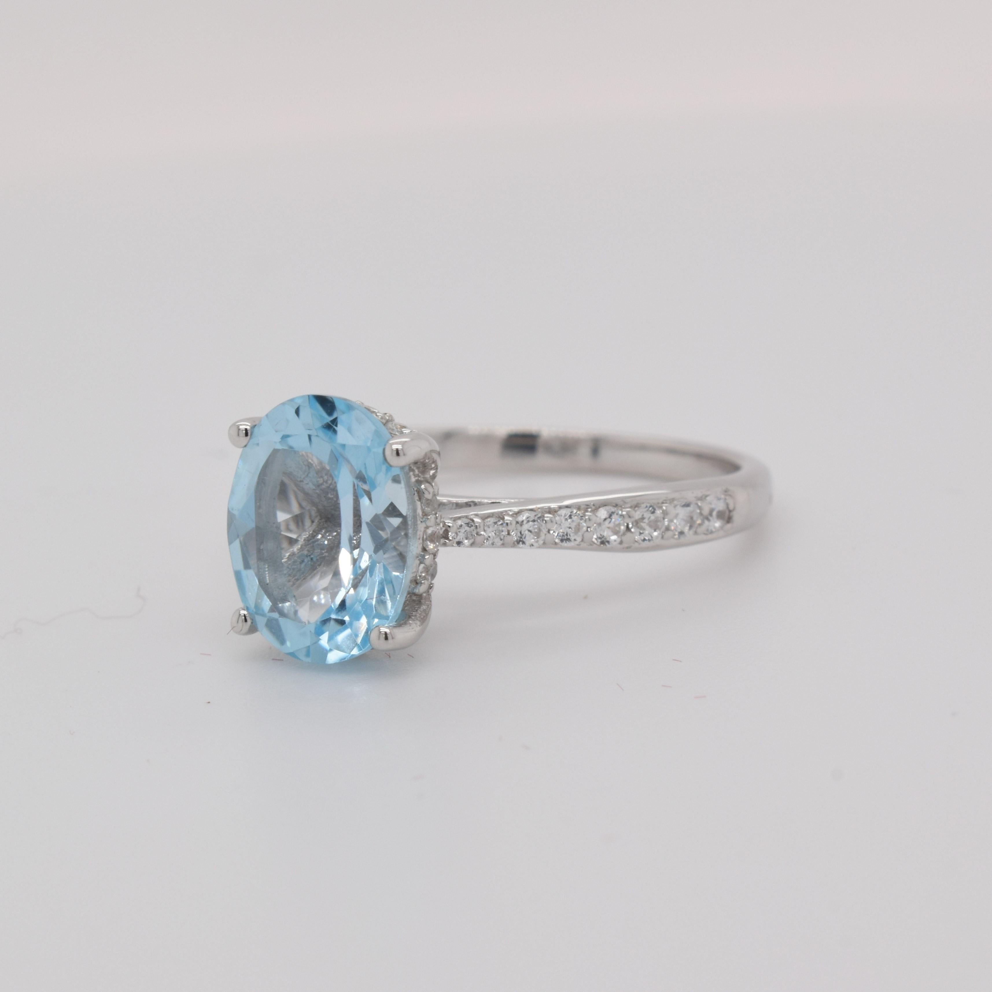 Oval Shape Sky Blue Topaz Gemstone beautifully crafted with CZ in a Ring. A fiery Blue color December Birthstone. For a special occasion like Engagement or Proposal or may be as a gift for a special person.

Primary Stone Size - 9x7mm