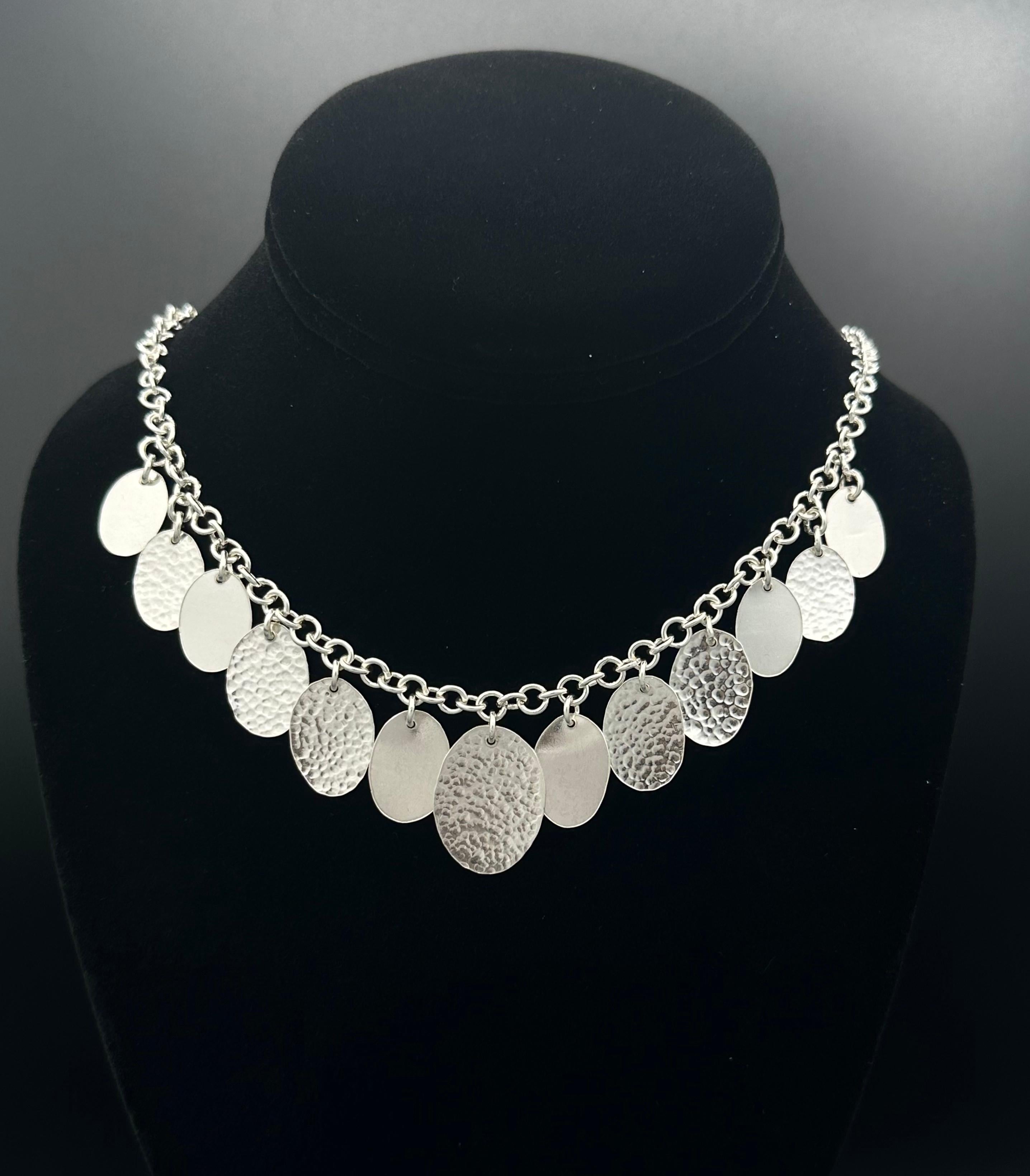 -Available 
-Handmade
-Sterling silver
-Stamped with Nebu logo
-17 inch

Introducing our exquisite handmade silver necklace, featuring charming oval disc drops that catch the light beautifully. Some of the discs are hammered by hand, while others