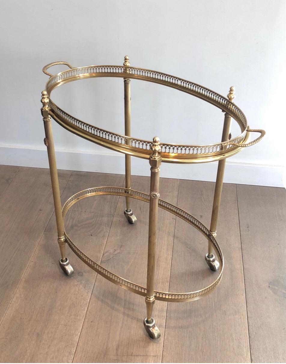 This very nice and decorative neoclassical style bar cart is made of brass with 2 glass trays. The top tray can be removable for service. This is a French work by Maison Jansen. Circa 1940