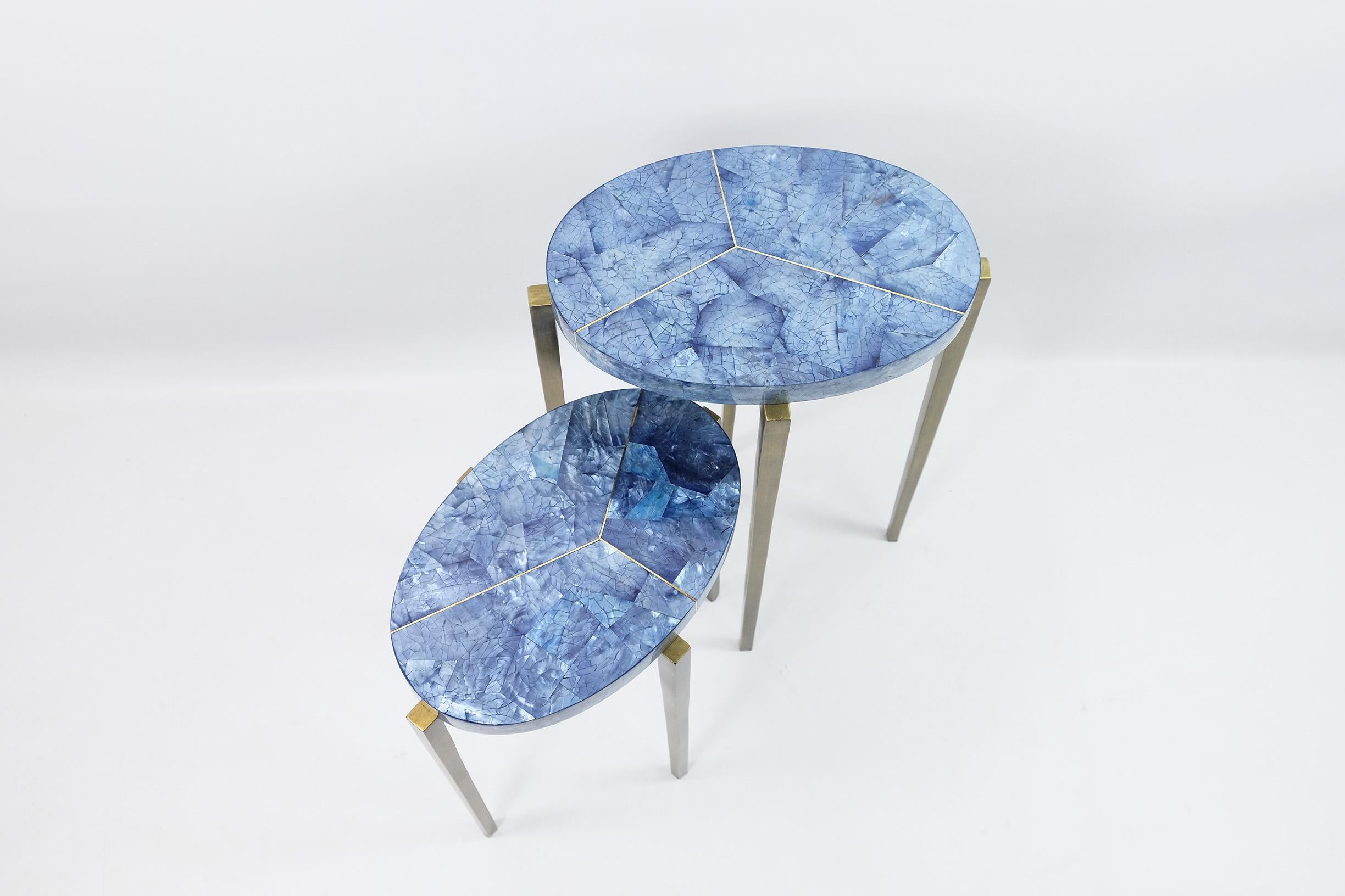 Diese schönen Nisttische sind aus poliertem blauem Intarsienholz mit Messingzierleisten gefertigt.

Sie haben eine ovale Form und die Metallfüße haben eine antike Messingpatina.

Die Tische sind klein und sehr vielseitig. Sie können überall in der
