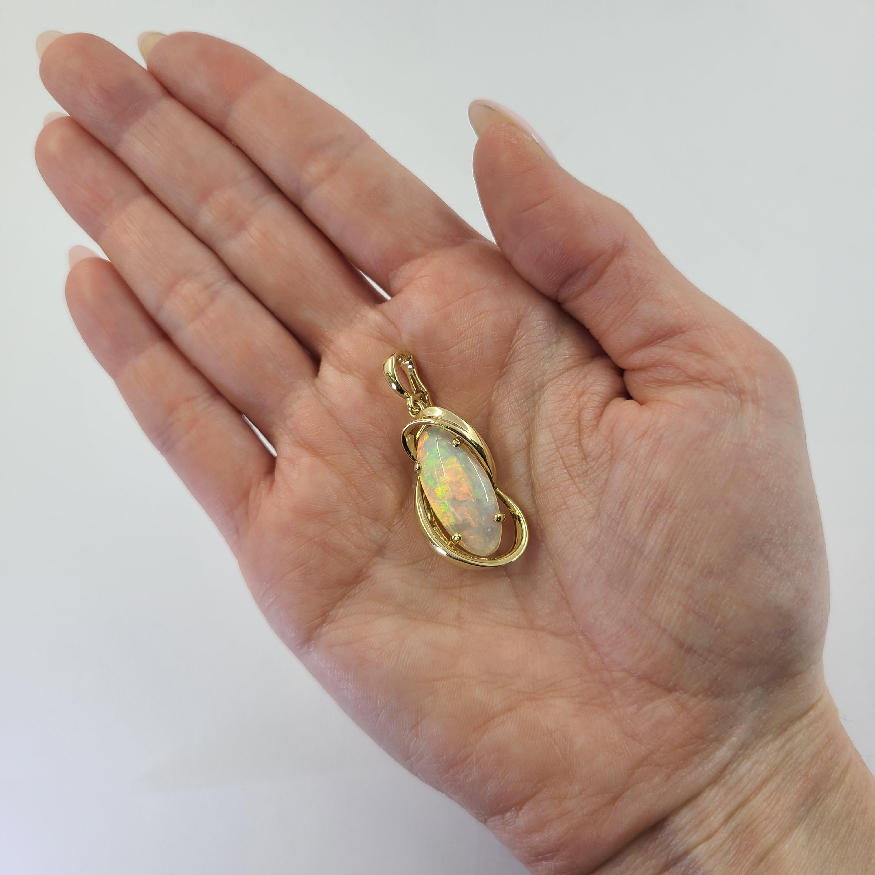 18 Karat Yellow Gold Enhancer Pendant Featuring An Oval Cabochon Opal Measuring 22mm x 10mm Estimated to Weight 5 Carats. White Body with Bright Red and Pink Flashes. Hinged Clip with Figure 8 Lock. Approximately 1.5 Inches in Length Including Bale.