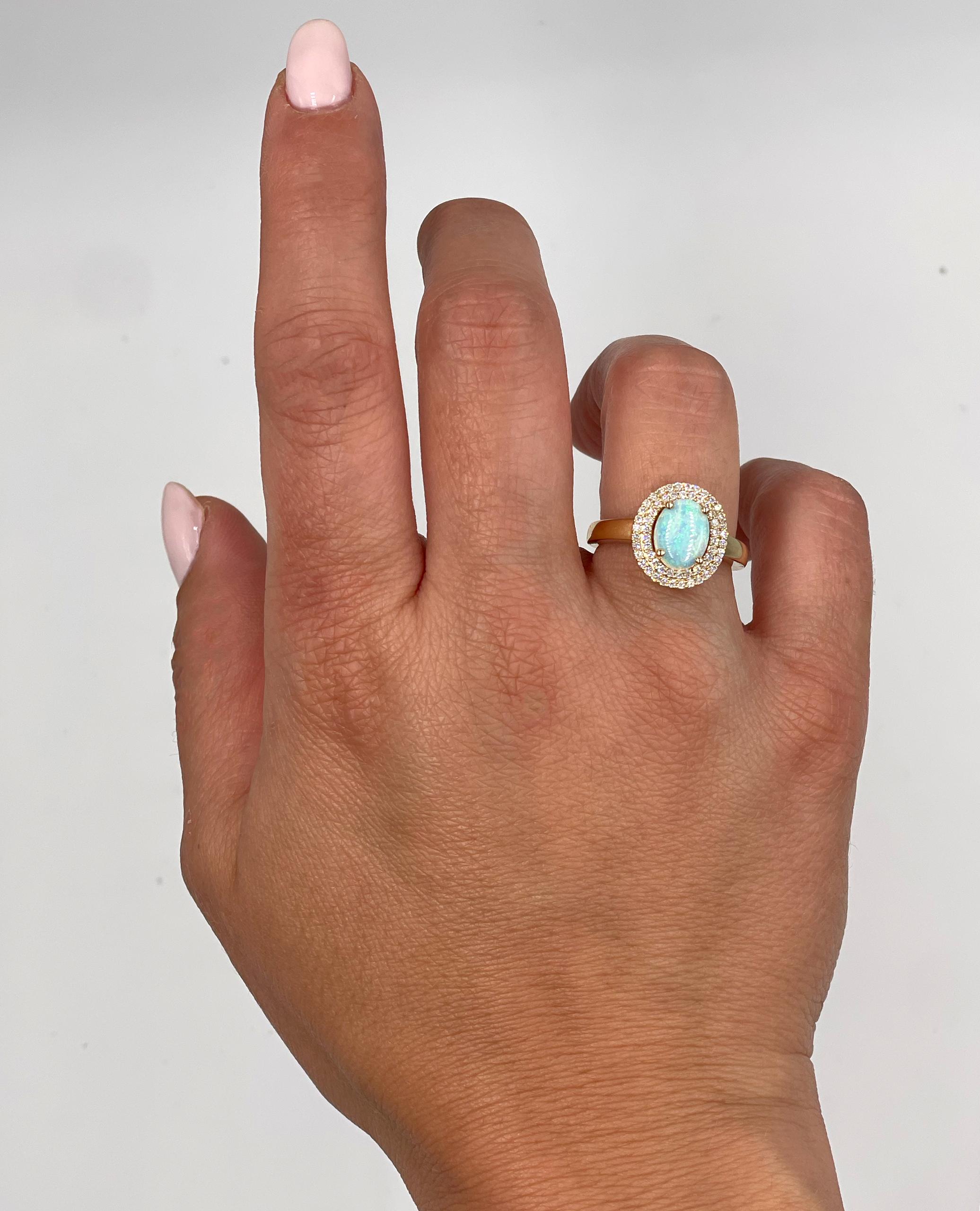 14K yellow gold ring with double halo of round brilliant cut diamonds weighing 0.29 carat total and one center oval prong-set opal weighing 1.05 carats. 

- Finger size 7, can be sized up or down by up to two sizes
- Diamonds are G/H Color, SI