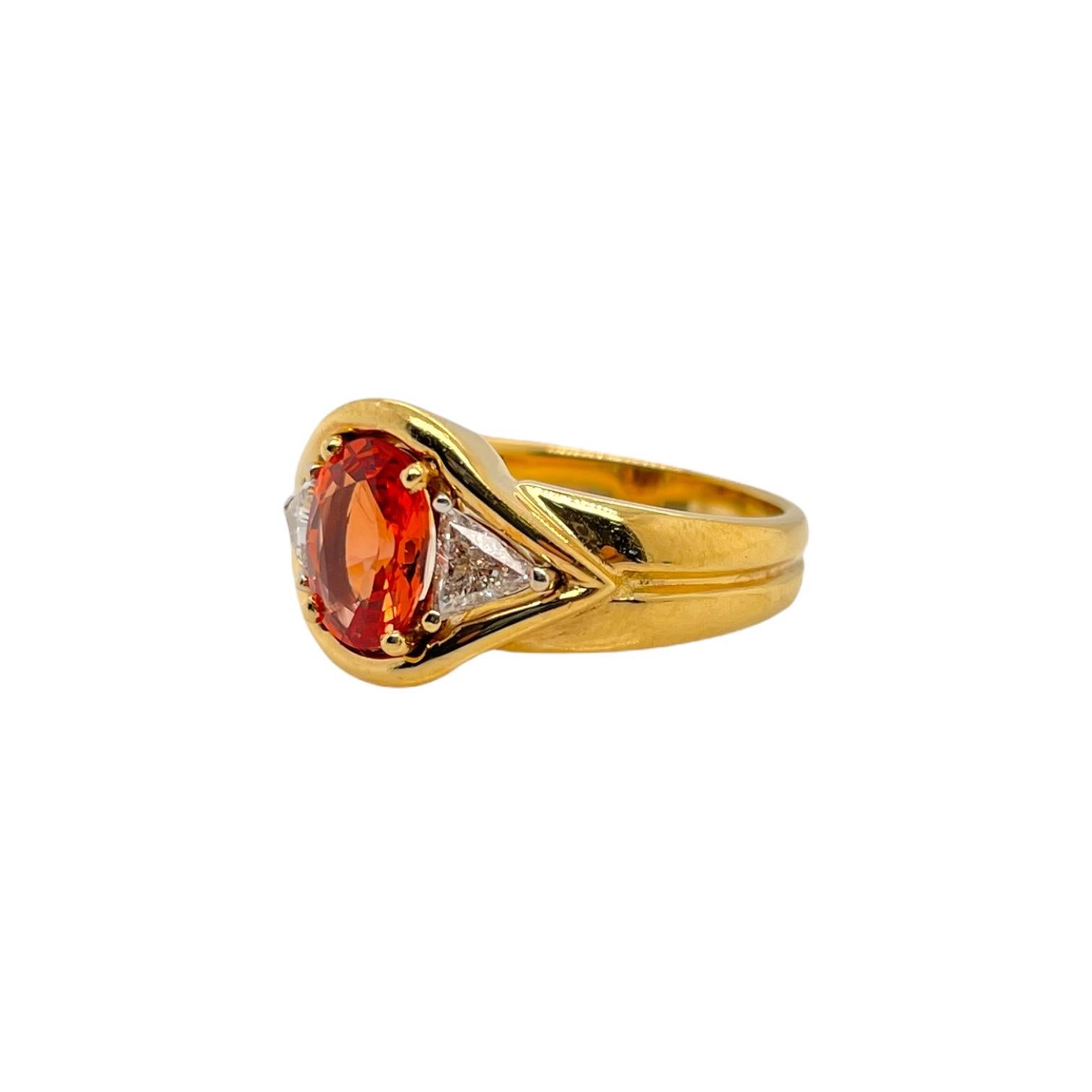 Oval orange sapphire and trillion cut diamond ring in 18k yellow and white gold. Ring contains 1 center 8x6mm oval orange sapphire 1.50ct and two side trillion cut diamonds 0.38tcw. Diamonds are G in color and SI1 in clarity. Stones are mounted in a