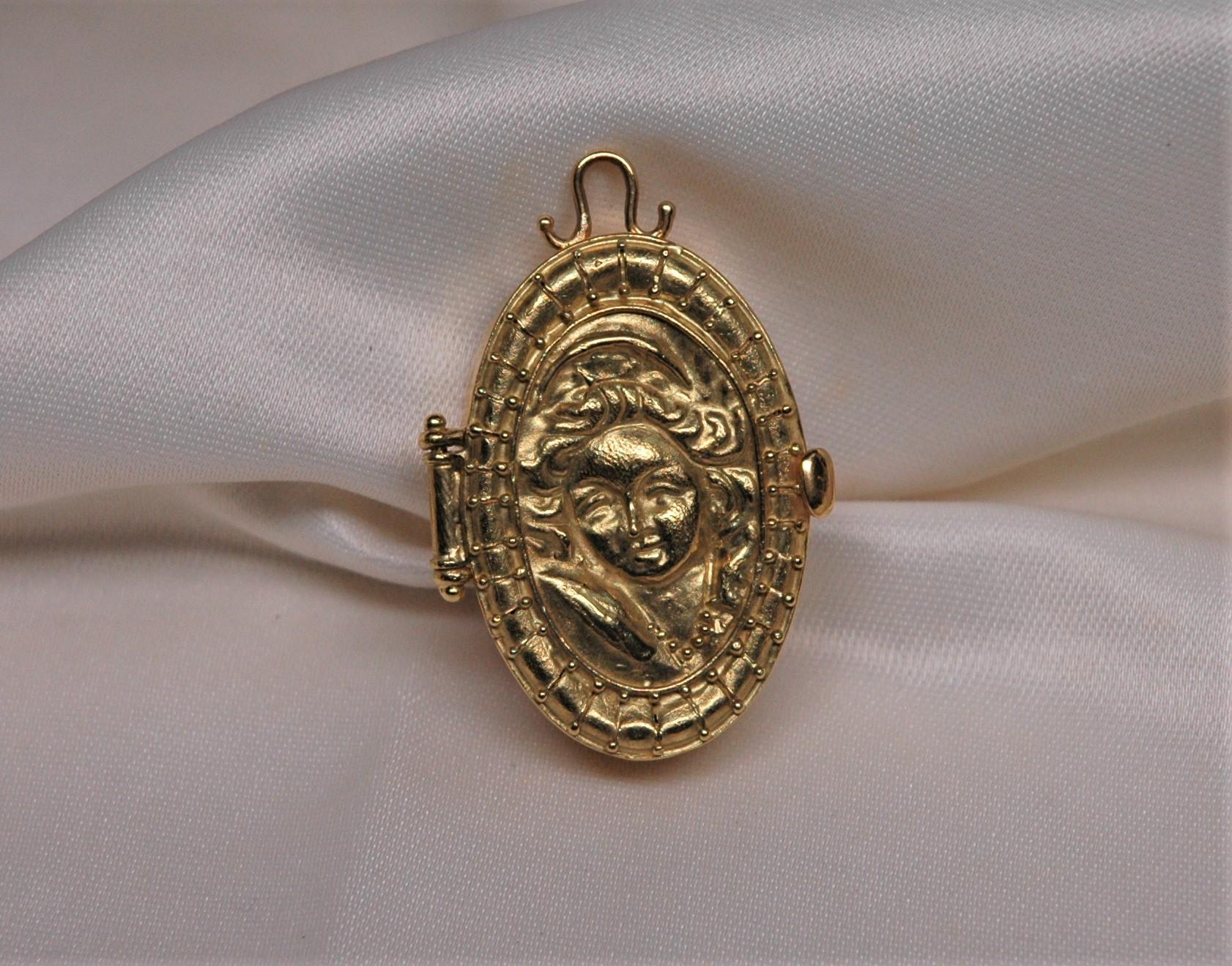 Oval box in 18 kt gold, wearable as a pendant. Hand-made with a woman's profile decoration. It can be opened.