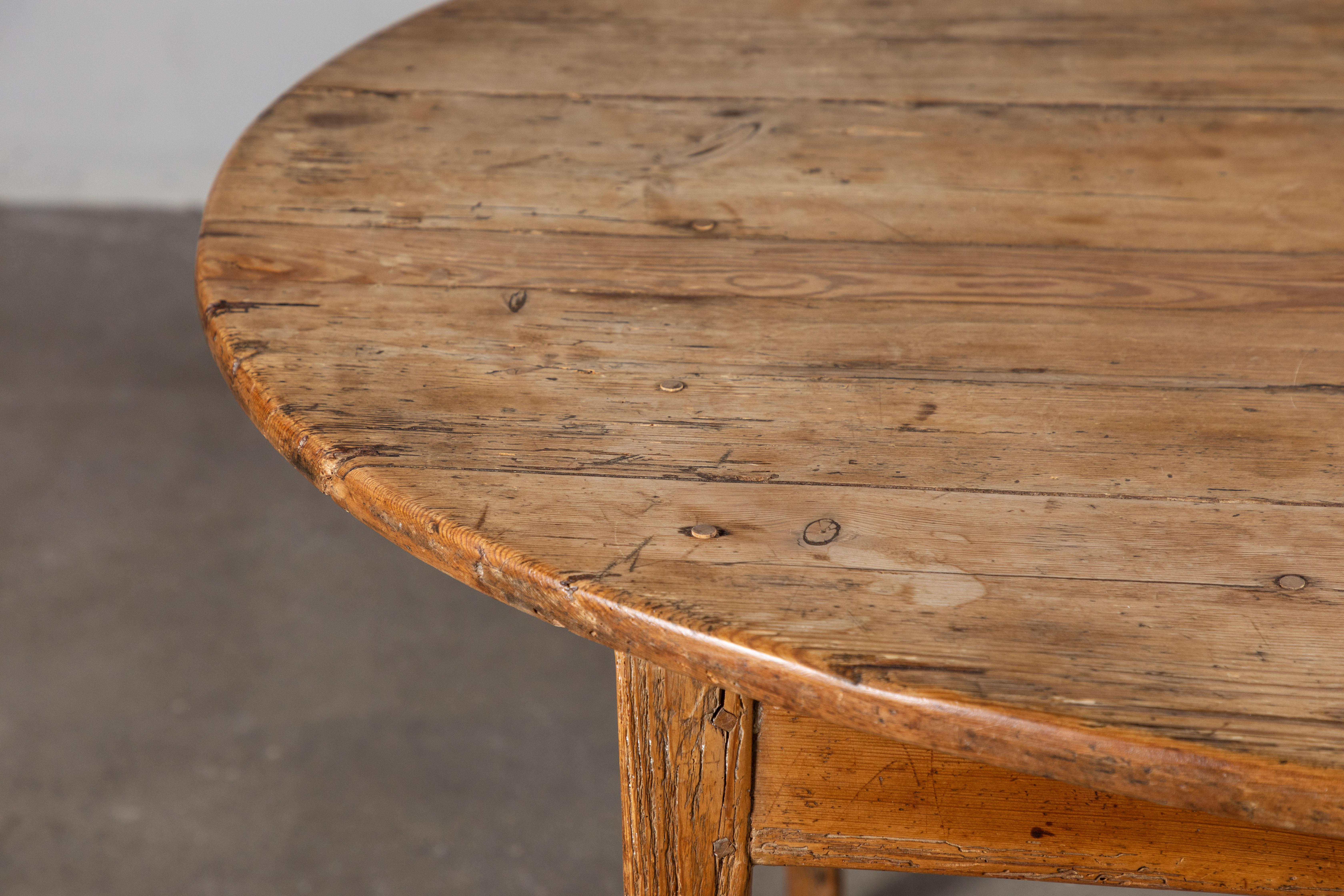 Rustic oval pine dining table with apron and tapered legs.