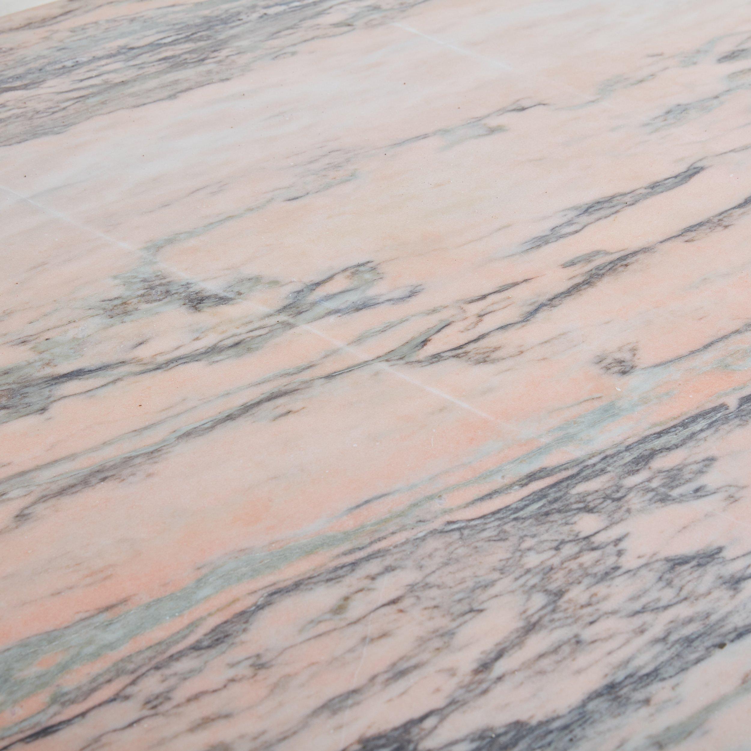 Table de salle à manger ovale en marbre rose portugais provenant d'Espagne, présentant une magnifique teinte rose avec des veines grises. Cette table a une finition adoucie et présente un plateau à bord arrondi et une base octogonale à facettes.