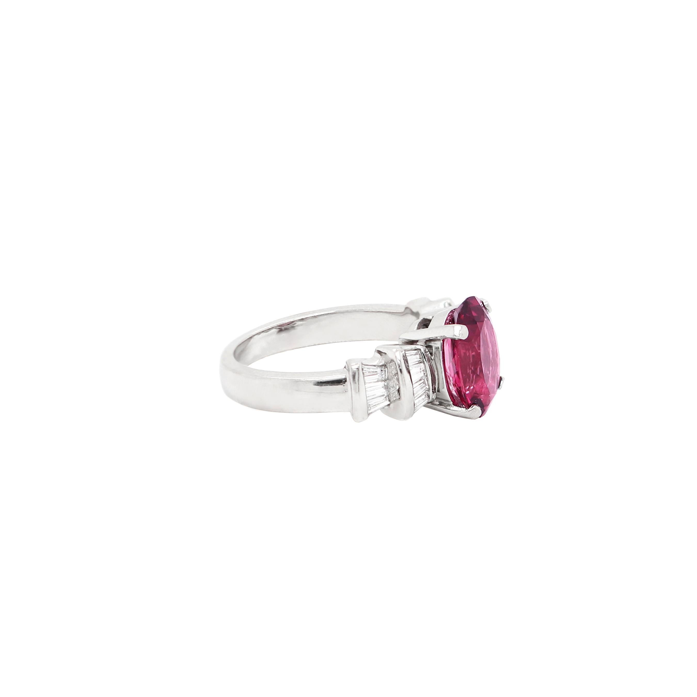 Dress ring featuring a beauiful oval shaped pink tourmaline weighing approximately 3.00ct in a four claw open back setting. The stone is accompanied by two channel set tapered baguette steps on either side, set with a total approximate diamond