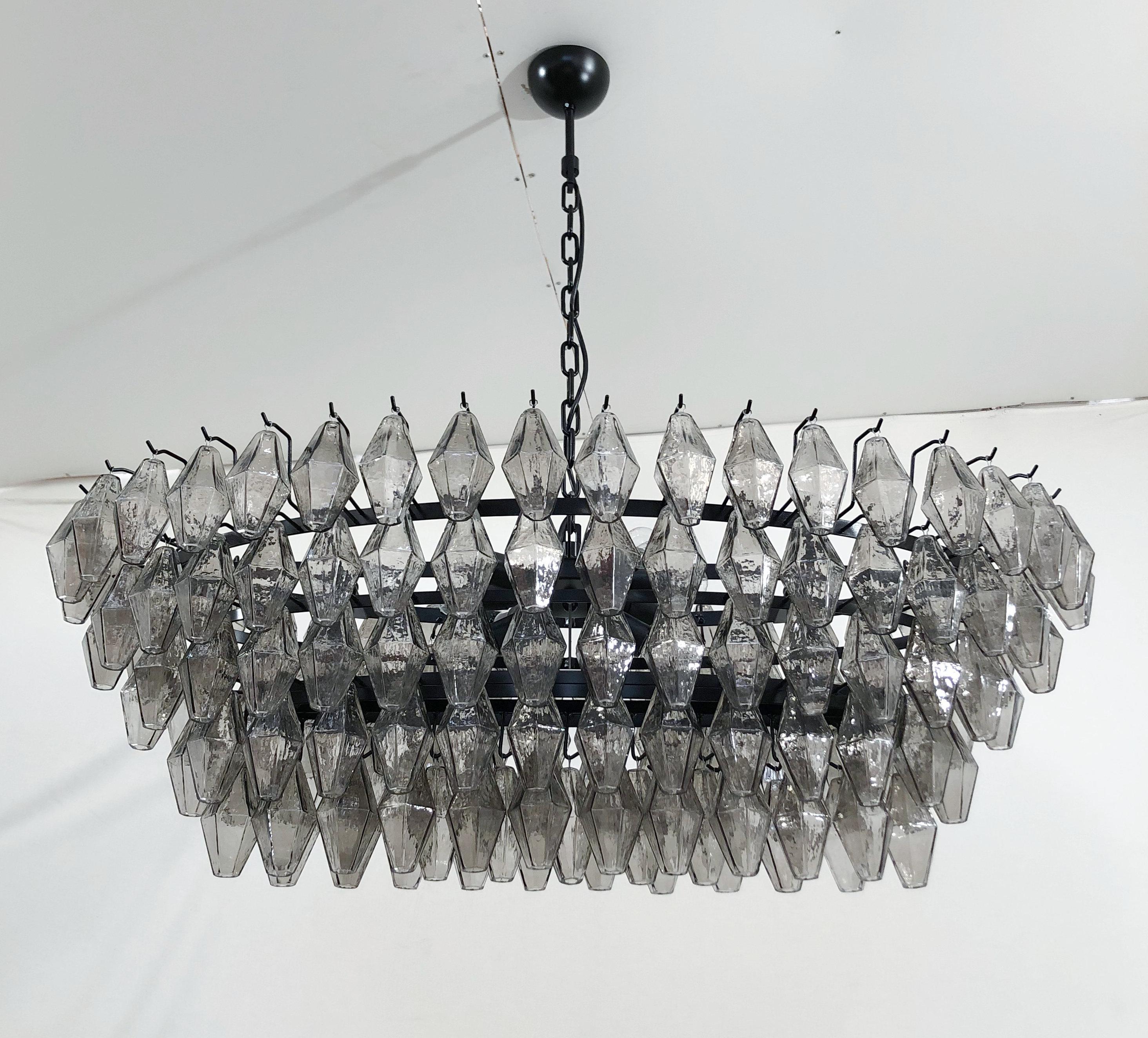 Italian oval shaped chandelier with smoky polyhedron / polyhedral shaped Murano glasses mounted on matte black powder coated finish frame / Made in Italy
Measures: Length: 47 inches, width 24 inches, height 16 inches plus chain and canopy
8 lights
