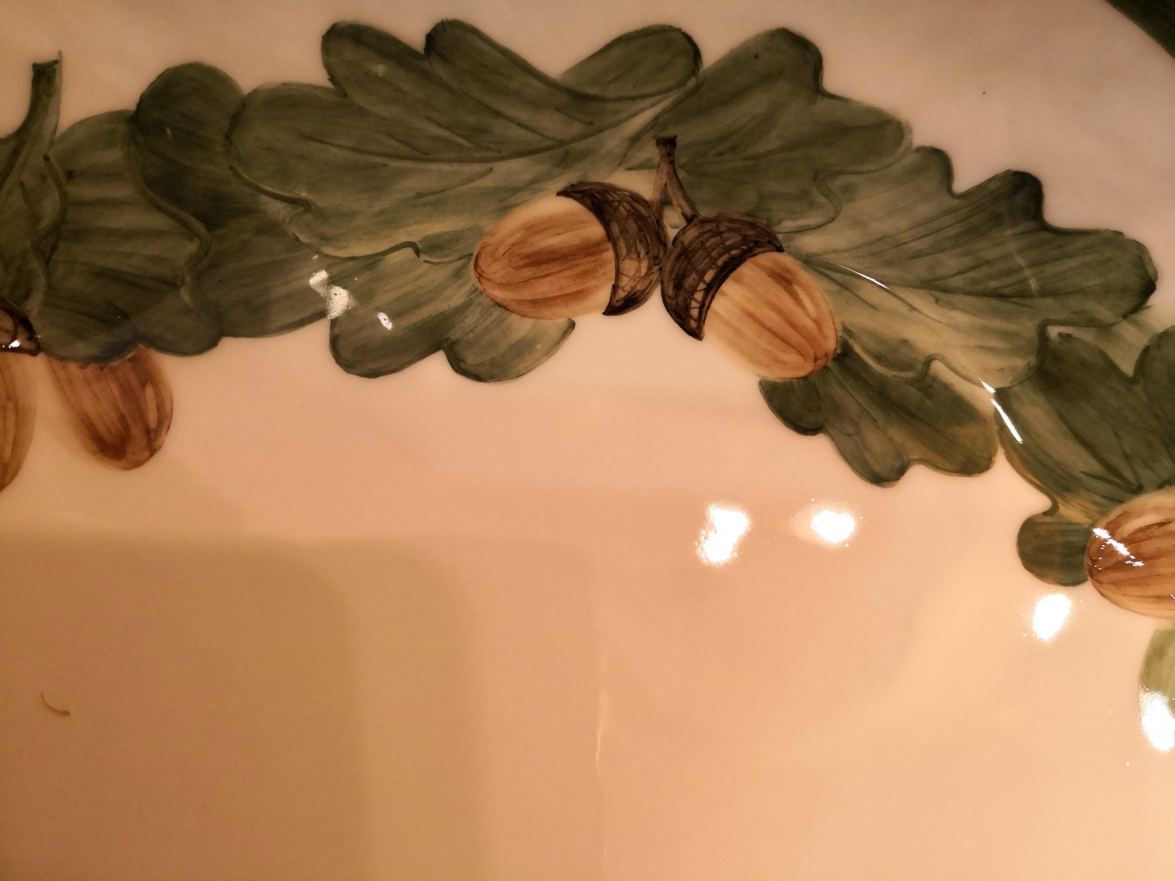Le plat en porcelaine entièrement fabriqué à la main est peint dans un décor traditionnel de la Forêt-Noire avec une guirlande naturaliste de feuilles de chêne. Le vert est bordé d'une fine ligne de platine. Il est magnifique avec des noix ou des