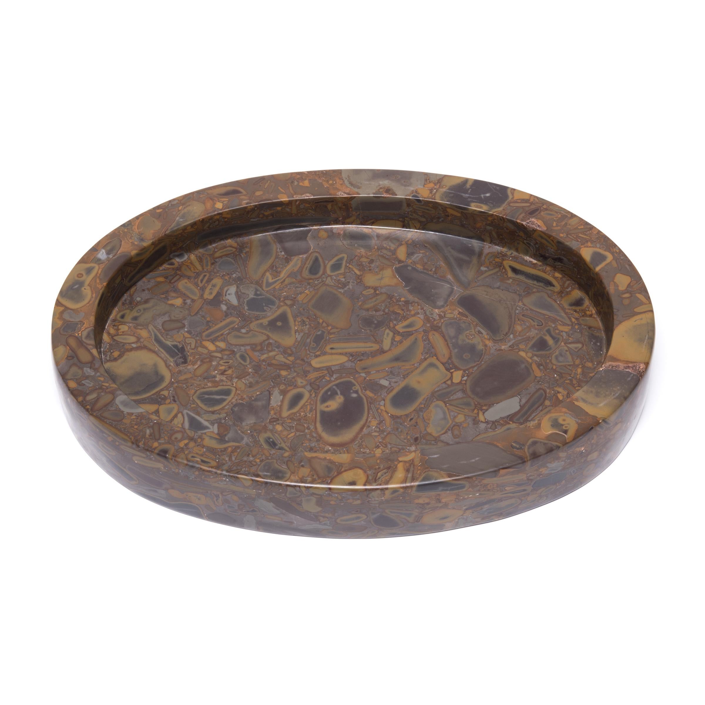 Uniquely patterned, this exceptional tray is hand carved from puddingstone. Named for its intriguing patterning, the conglomerate stone is embedded with pebbles of different minerals that look like pudding studded with raisins. Puddingstone was a