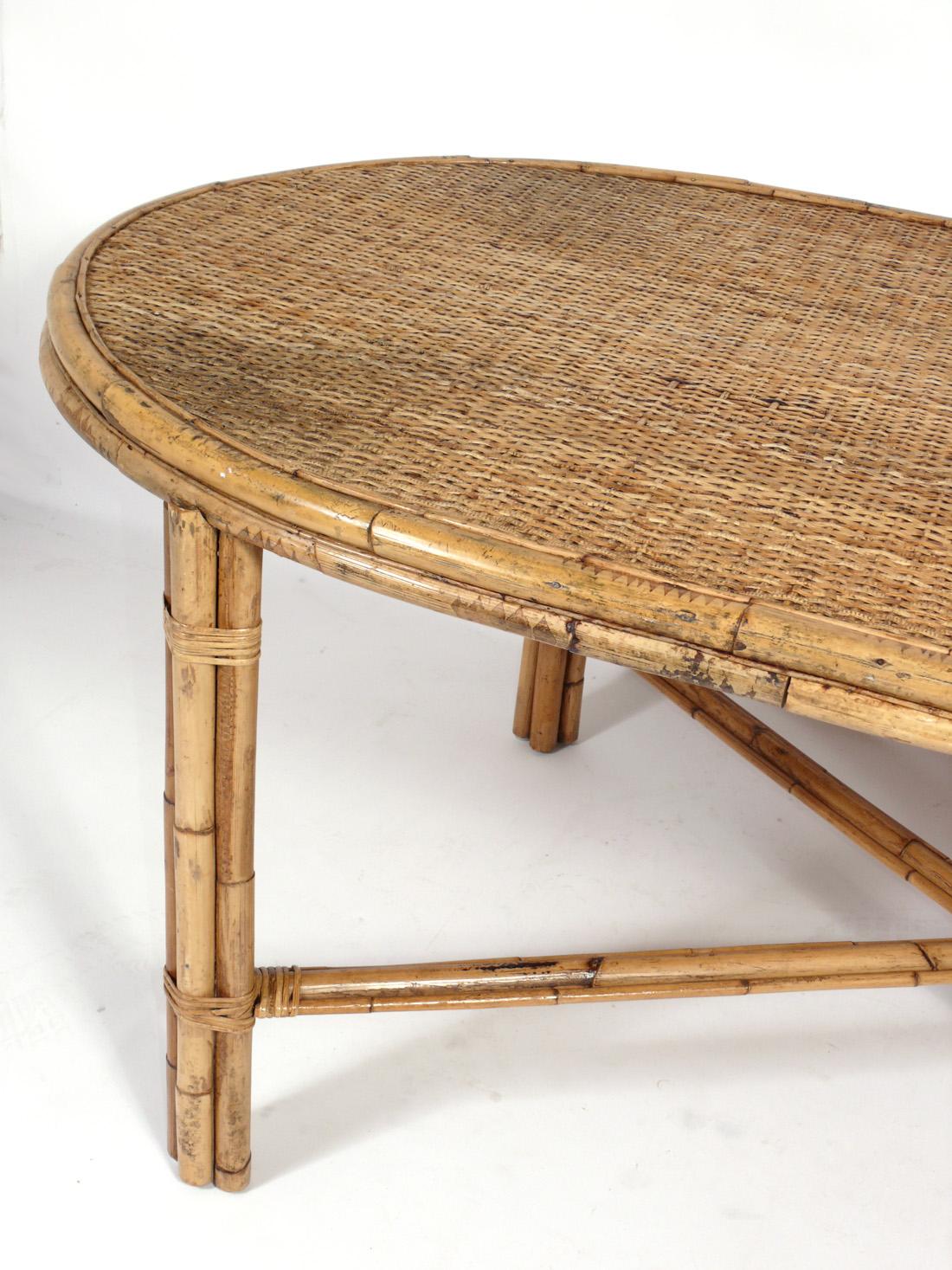 Oval racetrack shape rattan or bamboo dining table, American, circa 1960s. Retains warm original patina. 

 