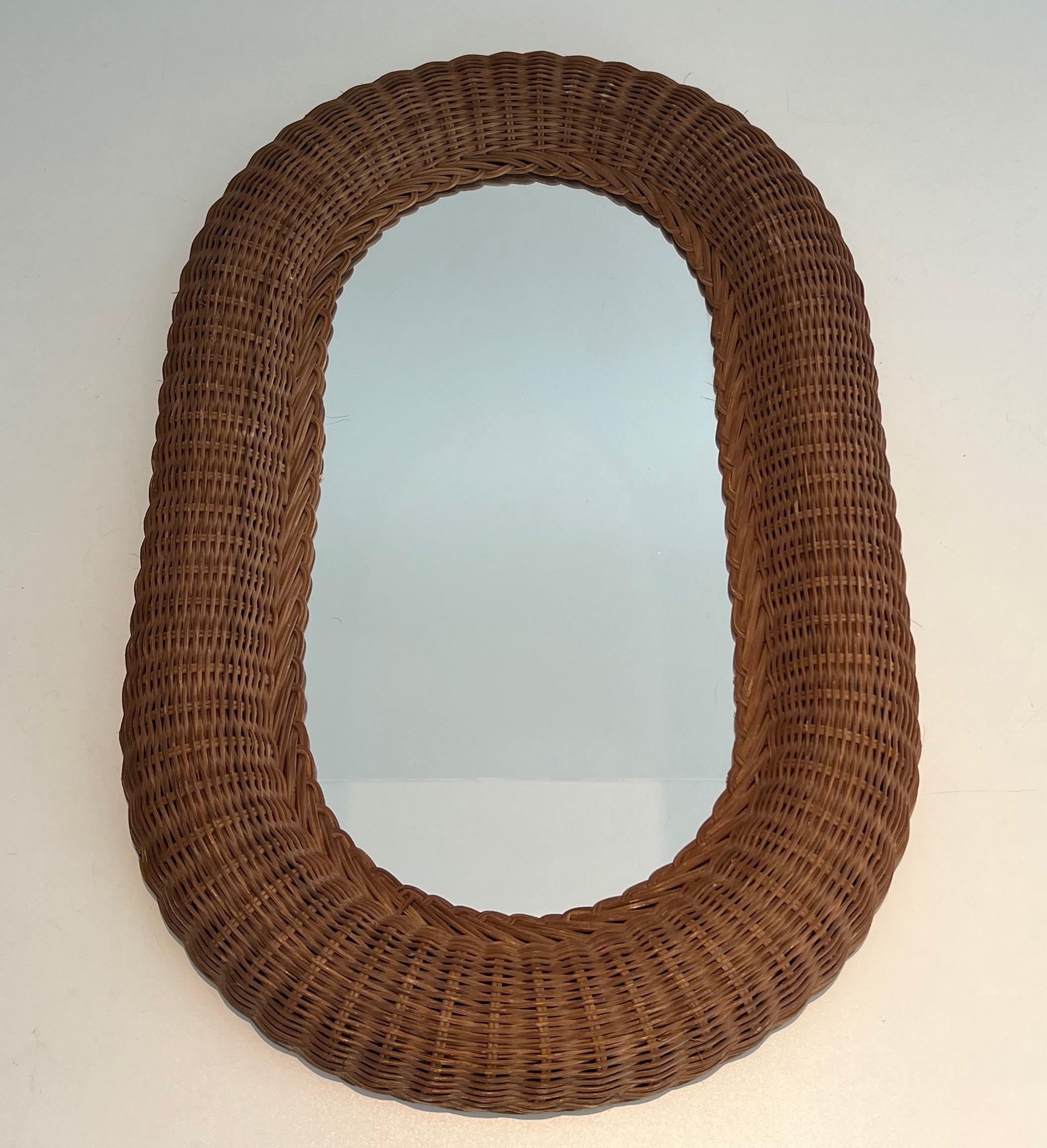 This unusual and decorative oval mirror is all made of rattan. This is a French work. Circa 1970