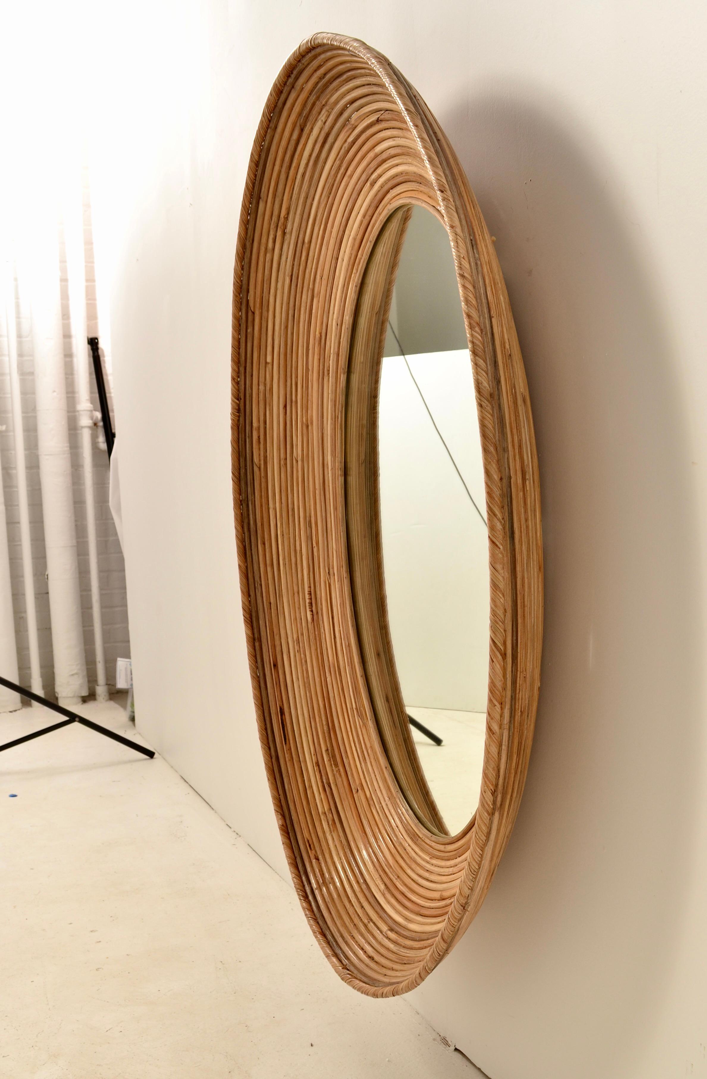 Large oval split reed rattan mirror. Great size and unusual oval shape in deep convex form. Very fine condition, new mirror glass. Can be hung either vertically or horizontally.