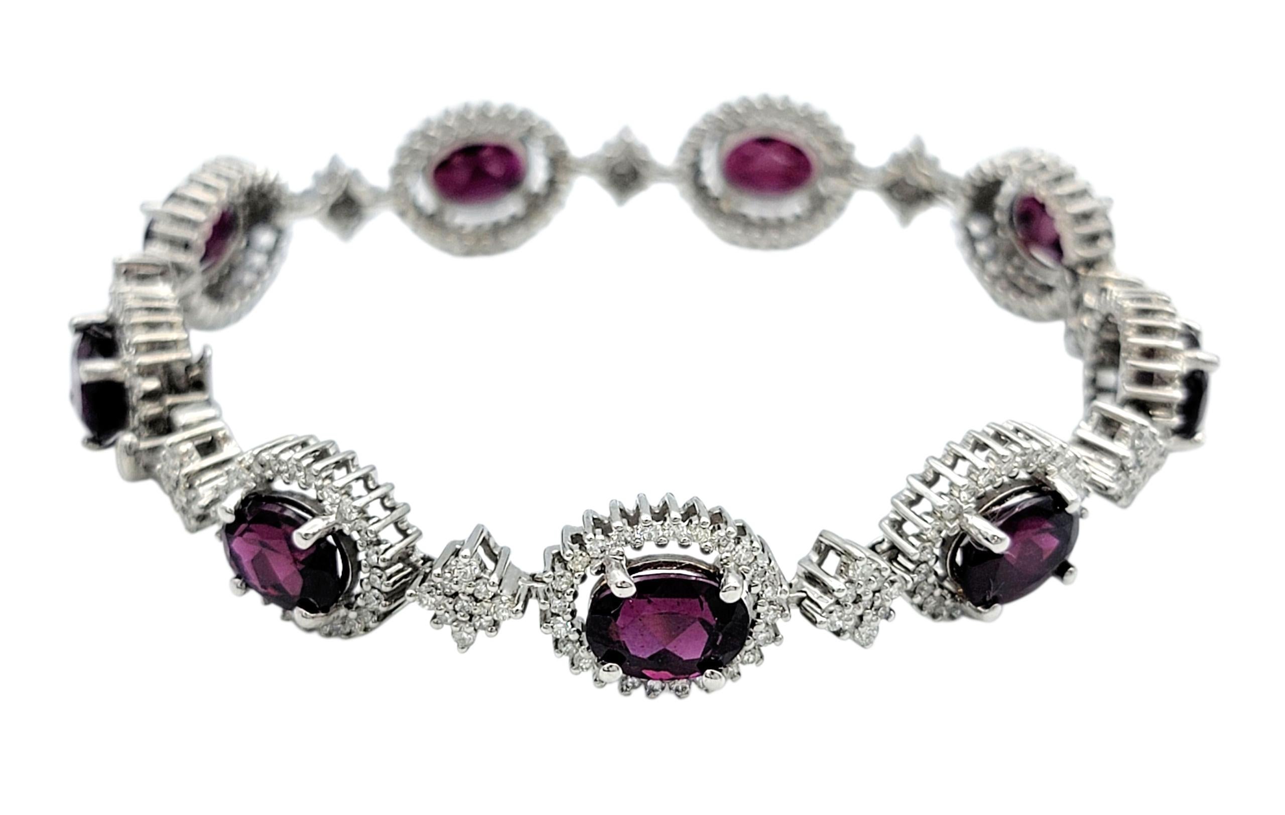 Ce bracelet accrocheur met en valeur neuf grenats rhodolites d'un rouge profond et violacé dans une forme ovale classique, chacun encadré par un éblouissant halo de diamants. Les pierres précieuses alternent dans leur position, formant une ligne