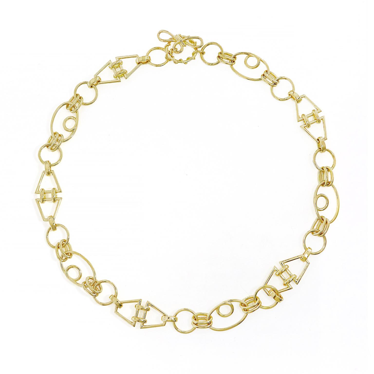 An eclectic arrangement of 18k yellow gold shapes are linked together. The pattern consists of a single circle which is connected by a pair of circles to an oval with a smaller circle in its center. Duos of parallel trapezoids are connected in