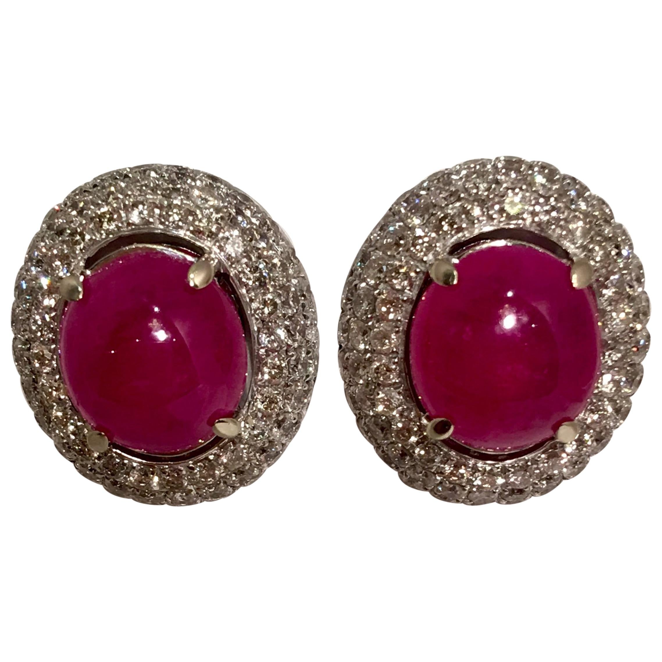 Striking 6 Carat Oval Ruby Cabochon Triple Diamond Halo White Gold Post Earrings For Sale