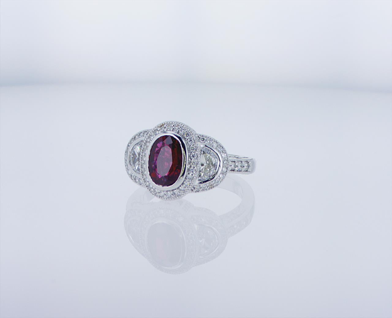 1.57ct Oval Ruby Cocktail Ring featuring 0.50ct Total Weight of Half Moon Diamonds and 0.55ct Total Weight of Round Diamonds in a Platinum Mounting.
