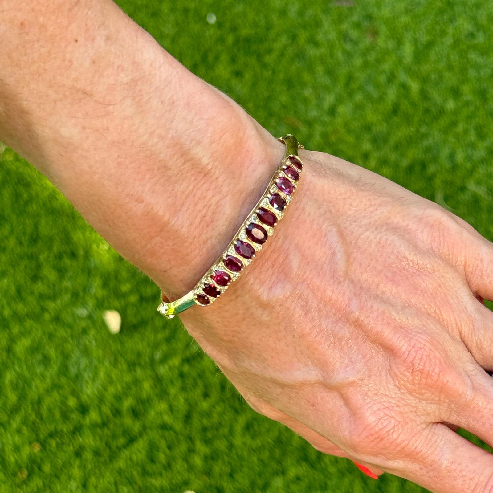 This exquisite vintage bangle is a beautiful blend of luxury and elegance, crafted in 14 karat yellow gold. The bangle features an eye-catching oval design, which gracefully encircles the wrist. At the center of the bangle lies a captivating array