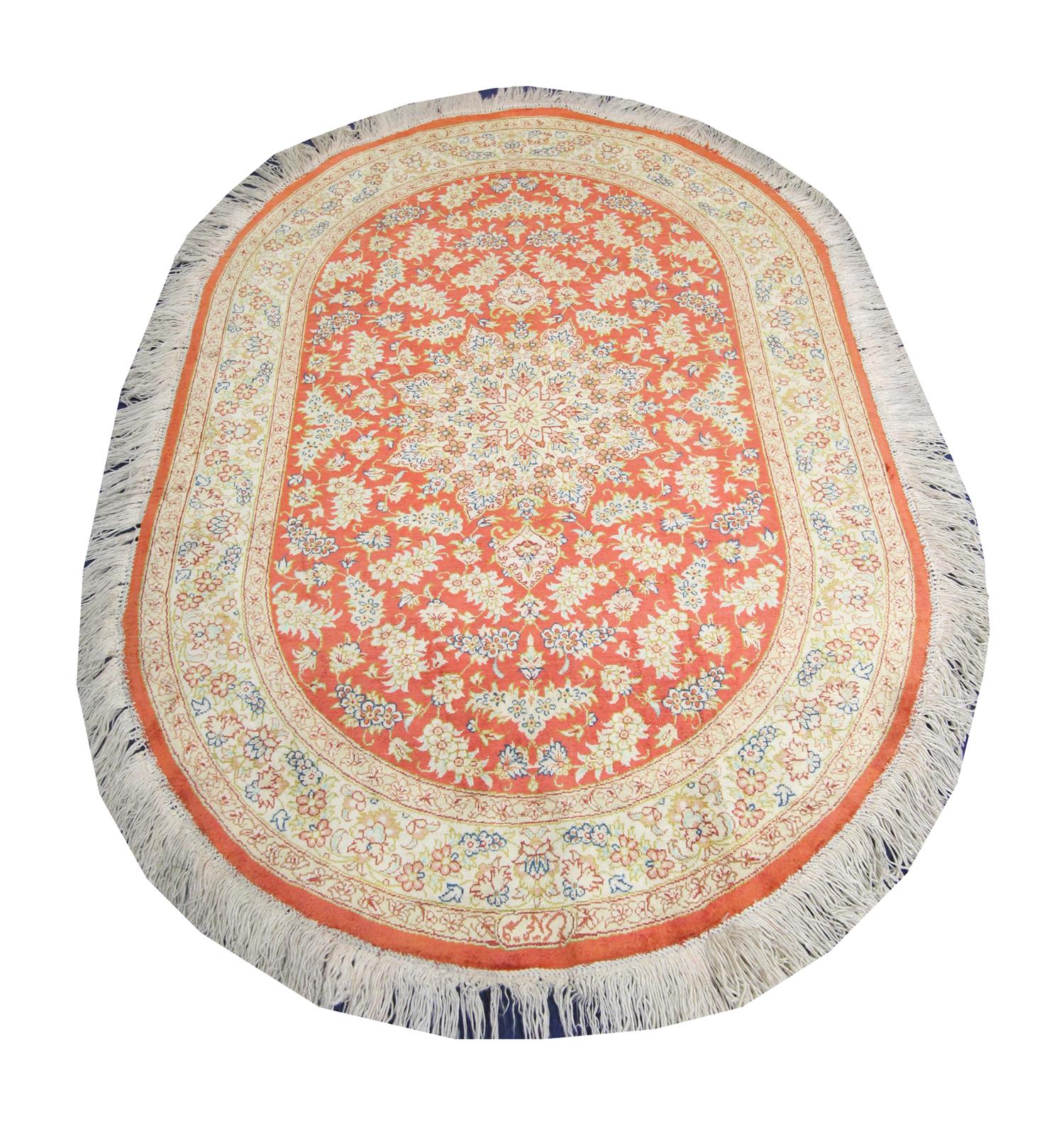 This fine pue silk rug was woven by hand in Turkey in the 1990s. It features a rich red-orange background with cream and beige accents that make up the symmetrical oriental medallion design. Decorated with delicate floral patterns. The unique colour