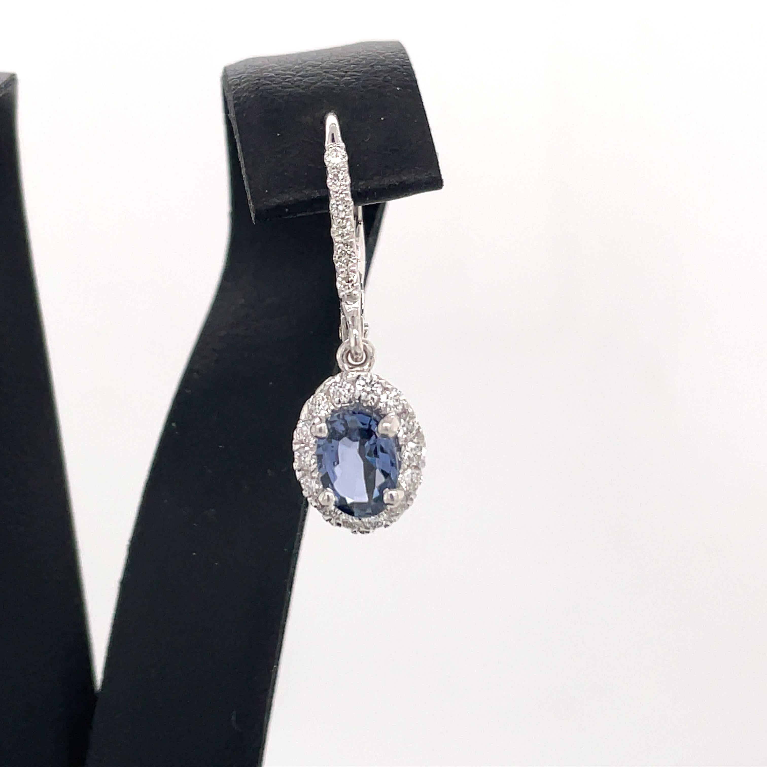 14 Karat white gold drop earrings featuring two Brillium treated oval shape Sapphires weighing 1.73 carats flanked with round brilliants weighing 0.53 carats. 