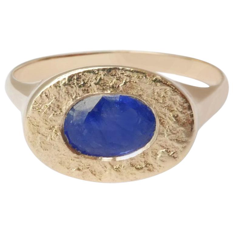 This textured signet ring features a natural oval-shaped Sri Lankan sapphire embedded in a shimmering texture crafted in solid 14-carat gold.  The ring is finished with a high polish on the sides and band for a comfortable fit.  This ring is a UK