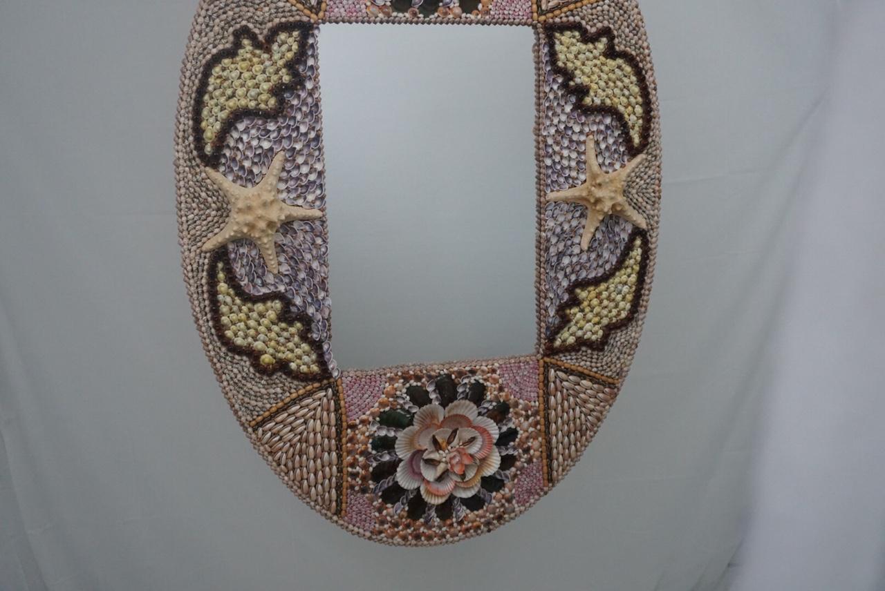 Tropical colors with punches of deep light pink and cream bring attention to this textural, oval seashell mirror. Only the best quality seashells used on this piece. This handmade mirror requires a crate and premium shipper. It is a piece of art and