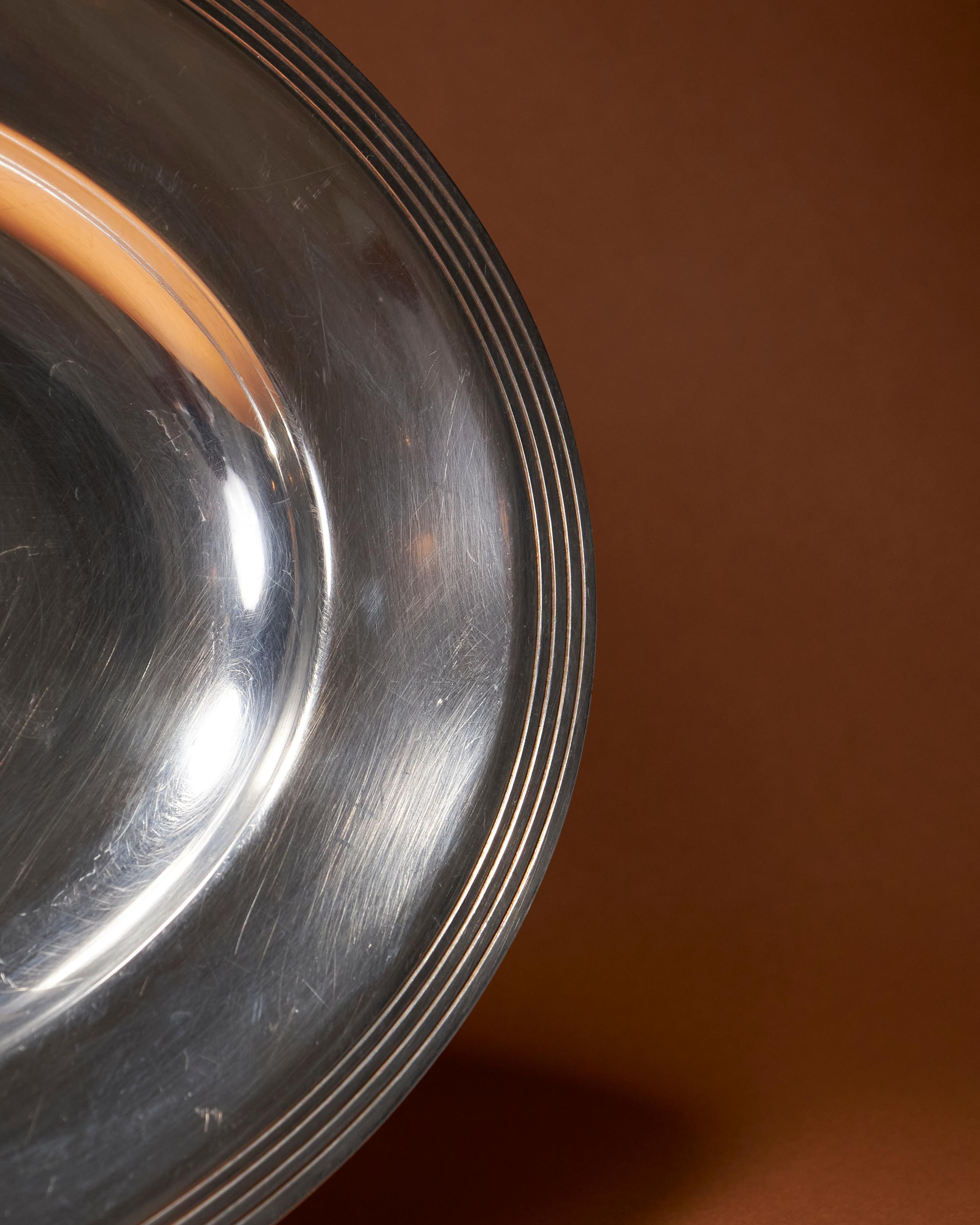 Plat de service ovale en métal argenté Christofle. Il est bordé de plusieurs bandes fines. Sa patine discrète reflète son élégance intemporelle et son authenticité. Poinçon de la marque sur la bordure.



