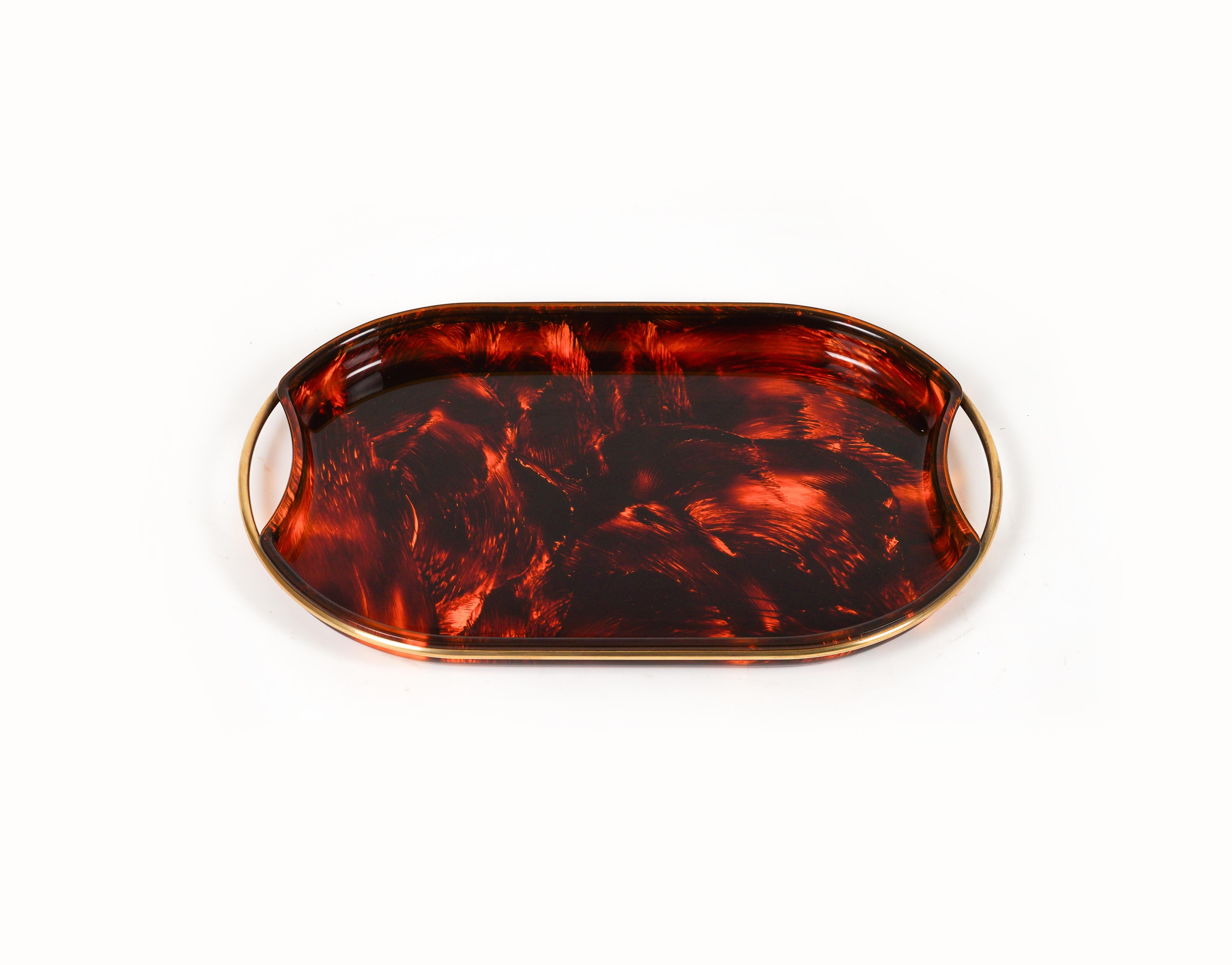 Midcentury amazing oval serving tray in faux tortoiseshell-effect Lucite featuring brass handles and borders by Team Guzzini.  

Made in Italy in the 1970s.  

It's an iconic tray or plate made of lucite that will wow your guests and is perfect for