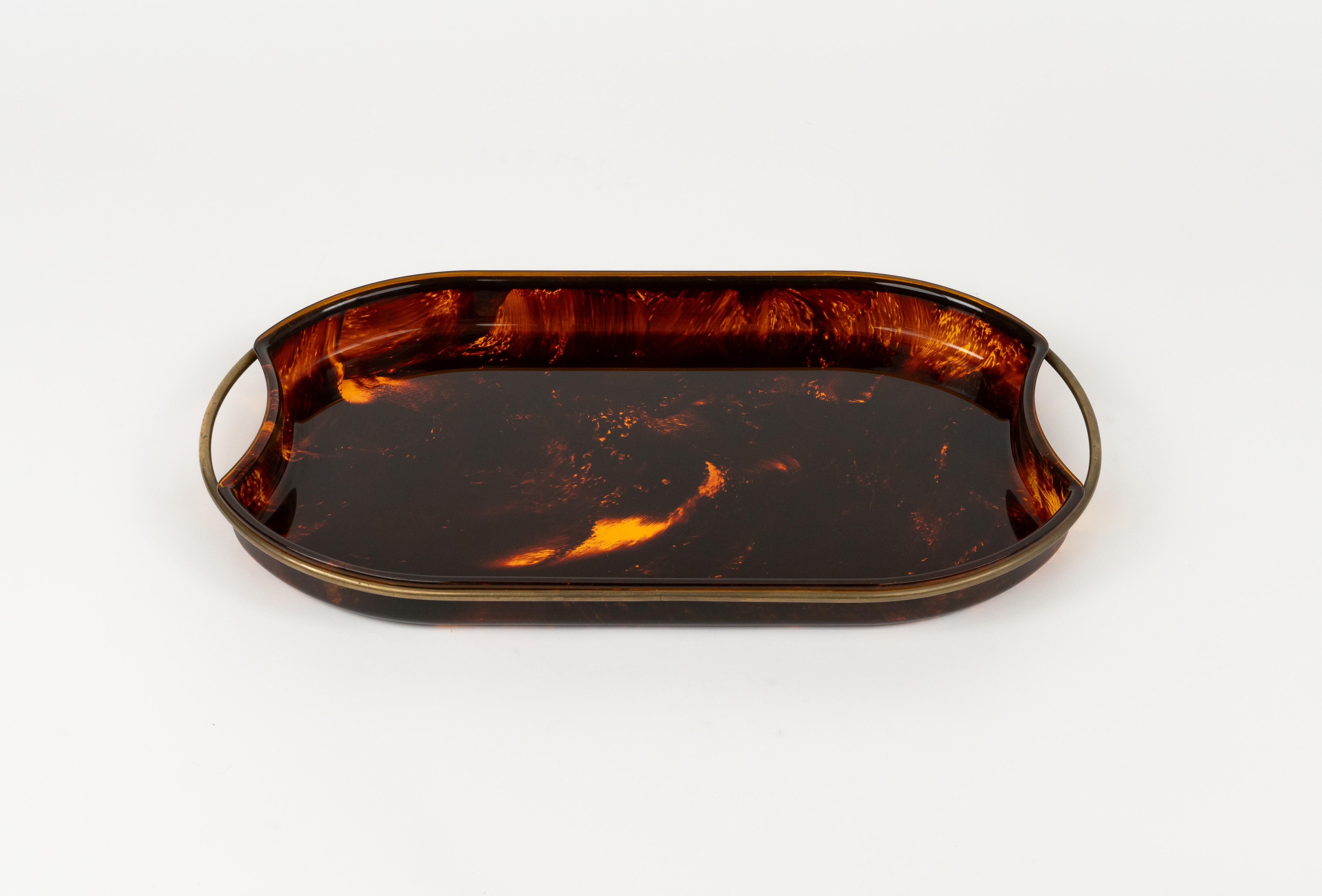 Midcentury amazing oval serving tray in faux tortoiseshell-effect Lucite featuring brass handles and borders by Team Guzzini.   

Made in Italy in the 1970s.   

It's an iconic tray or plate made of lucite that will wow your guests and is perfect