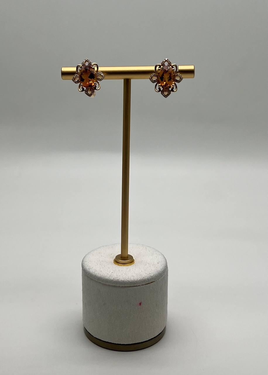These exquisite earrings showcase vibrant orange Citrines set in an intricate floral design. The central stones are surrounded by delicate, swirling metalwork and accented with sparkling white diamonds, creating a captivating contrast. 14K Yellow