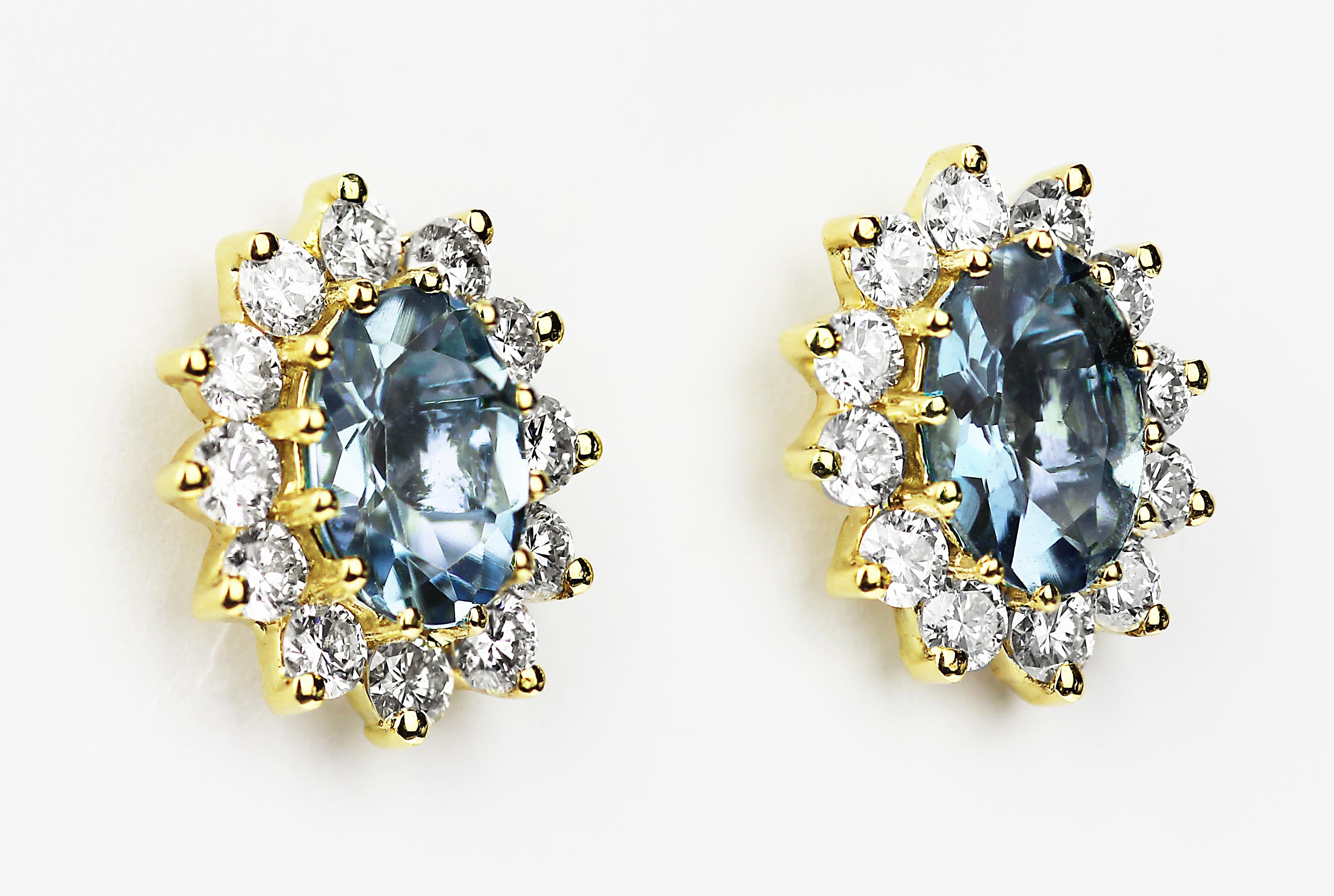 Stunning pair of aquamarine cluster earrings, the deep sea blue of the oval shape aquamarine, is ever so gentle sky blue colour whilst complimenting round brilliant cut diamonds all glistening and sparkling to create a chic flower design with a