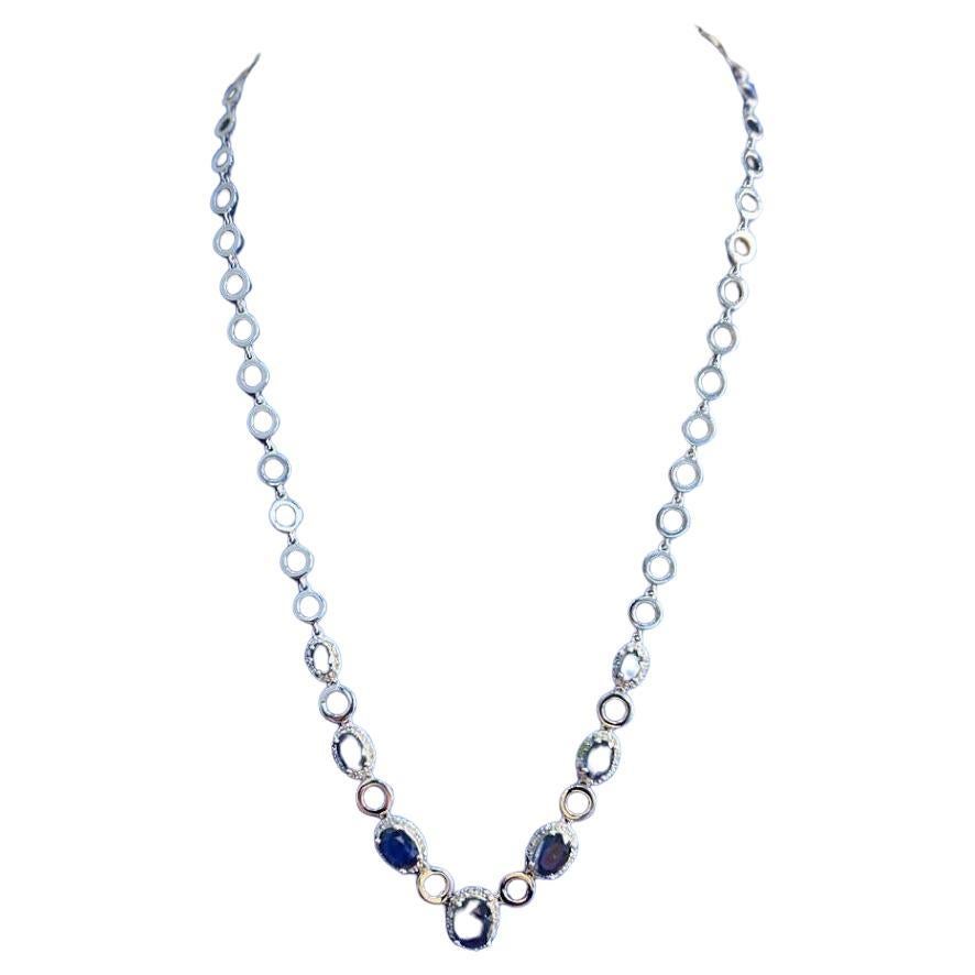 Questa collana di grande effetto è caratterizzata da una serie di maglie circolari con una finitura elegante e lucida. Il design è accentuato da una sequenza di zaffiri ovali di colore blu intenso, ciascuno circondato da un'aureola di diamanti