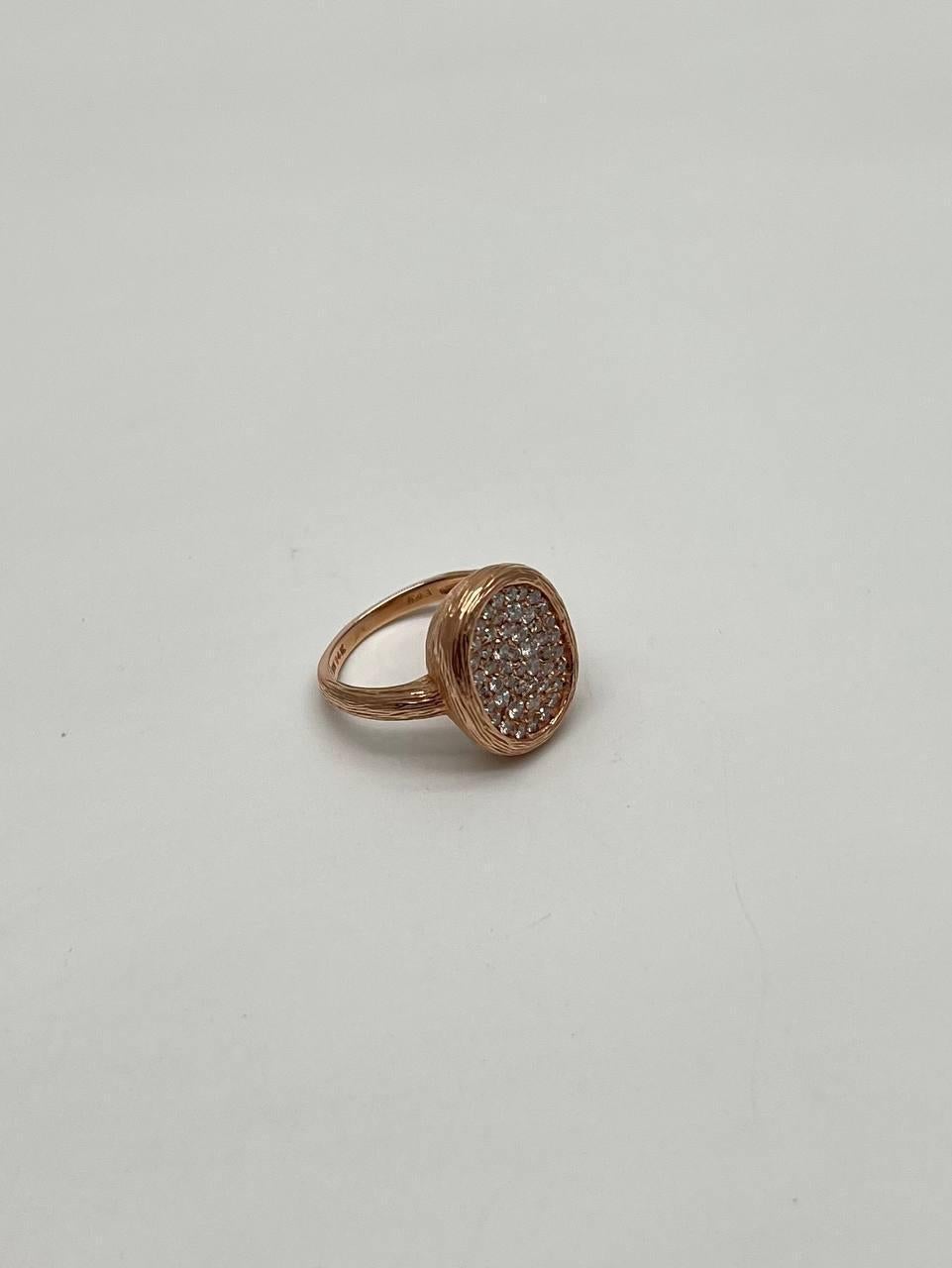 Questo elegante anello è realizzato in oro rosa. Il quadrante è di forma ovale ed è ornato da un gruppo di diamanti rotondi e scintillanti. I diamanti sono incastonati meticolosamente, creando una superficie abbagliante che cattura magnificamente la
