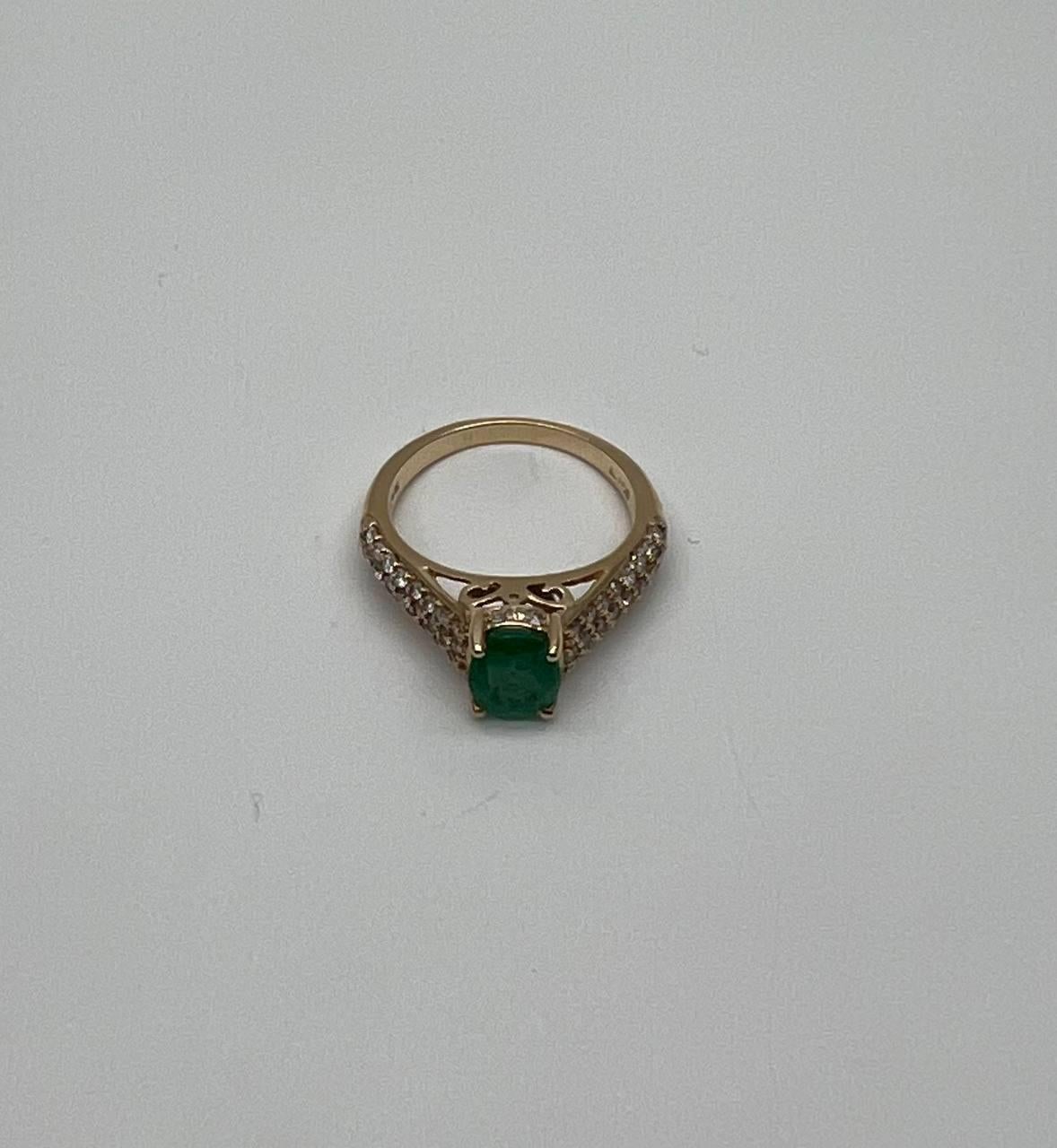 A luxurious Emerald and Diamond Ring, featuring a captivating emerald set in a gold band, adorned with sparkling diamonds. 14K Yellow Gold. 0.52 CTW Diamonds. 1.14 Cts Emerald
