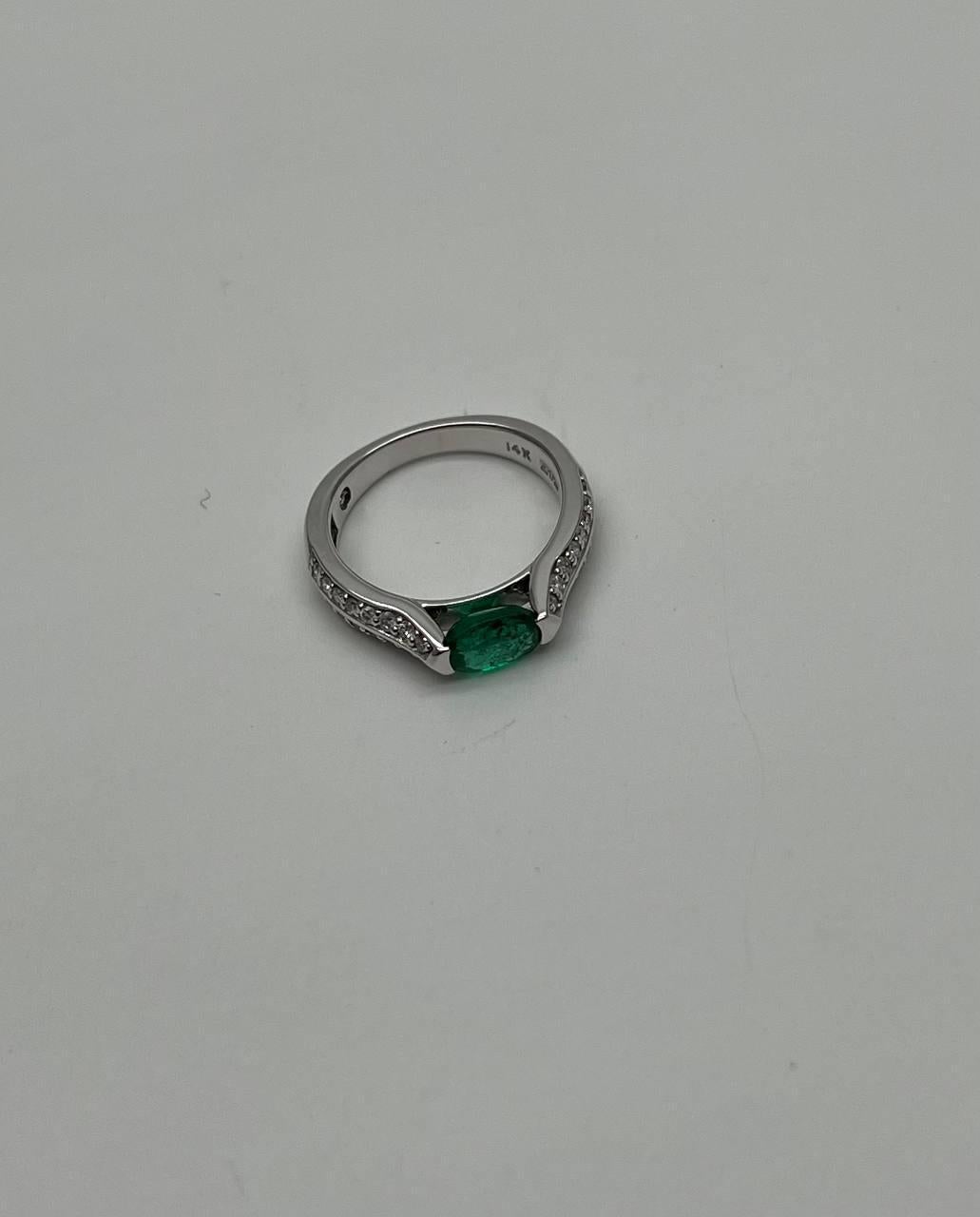 Una fusione di eleganza e modernità. Questo straordinario anello presenta un affascinante smeraldo di 0,76 carati dal taglio ovale, che irradia una ricca tonalità di verde. Accanto alla pietra centrale ci sono scintillanti diamanti bianchi, per un