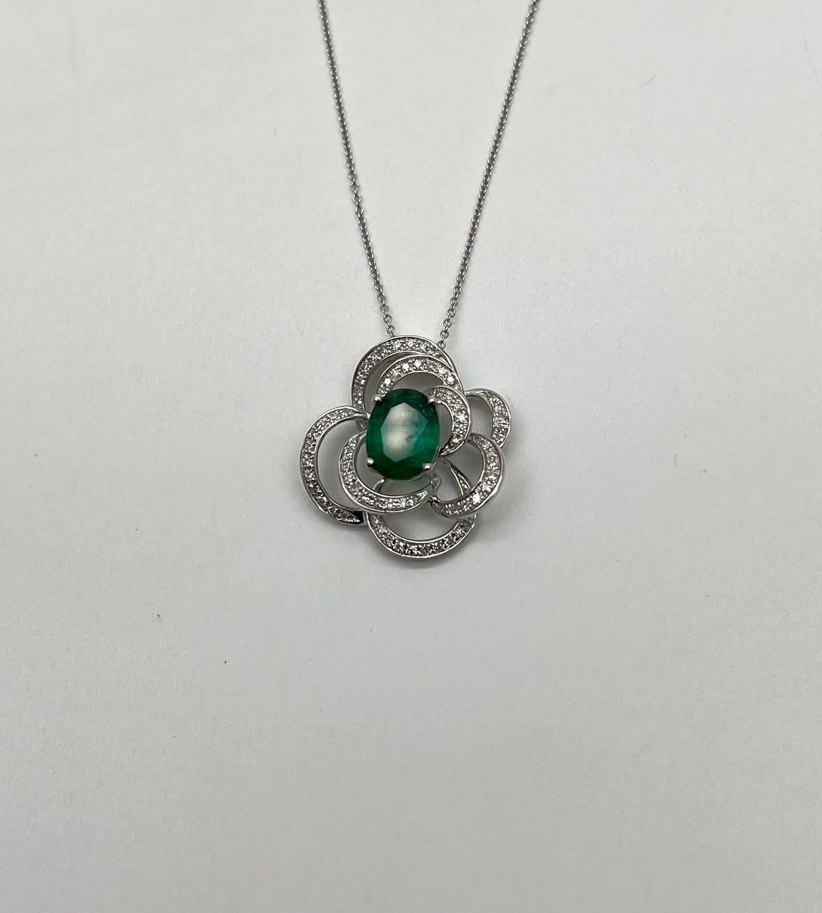 A captivating pendant necklace featuring a central green emerald encircled by intricate loops adorned with sparkling diamonds. 14K White Gold. 0.30 CTW White Diamonds. 1.52 Cts. Natural Emerald