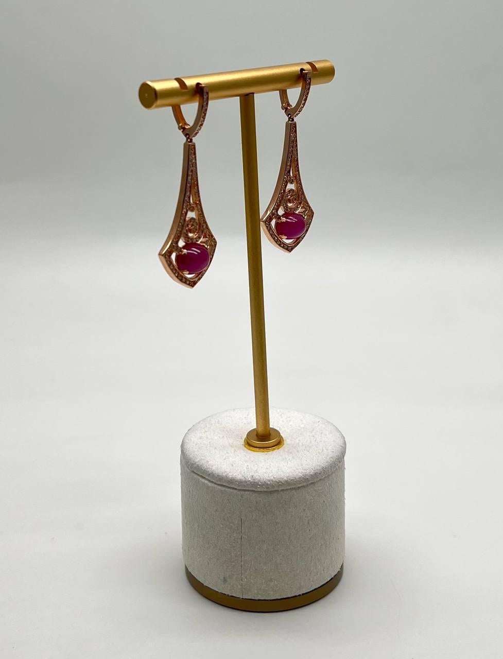 Squisiti orecchini dal design accattivante con intricate volute. Ogni pezzo presenta un vibrante rubino rosa rosso cabochon, elegantemente incastonato in una delicata cornice traforata. Eleganza moderna in ogni dettaglio. Oro rosa 14K. 0,70 CTW