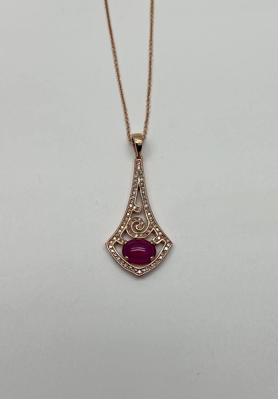Una collana con ciondolo di grande effetto. Questo pezzo presenta un rubino cabochon centrale di colore rosso con una tonalità ricca e profonda. Il rubino è circondato da un intricato disegno traforato ornato da piccoli diamanti scintillanti, che