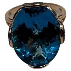 Bague cocktail halo champagne en or rose 14 carats avec topaze bleue suisse de forme ovale