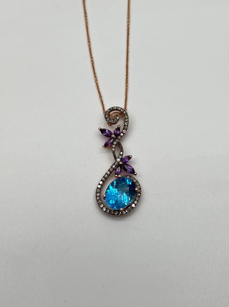 A stunning pendant necklace, this exquisite piece features a large, vibrant blue topaz set in a delicate swirl design.
The pendant is adorned with sparkling diamonds, enhancing its elegance and charm.
Accents of purple amethysts add a touch of color