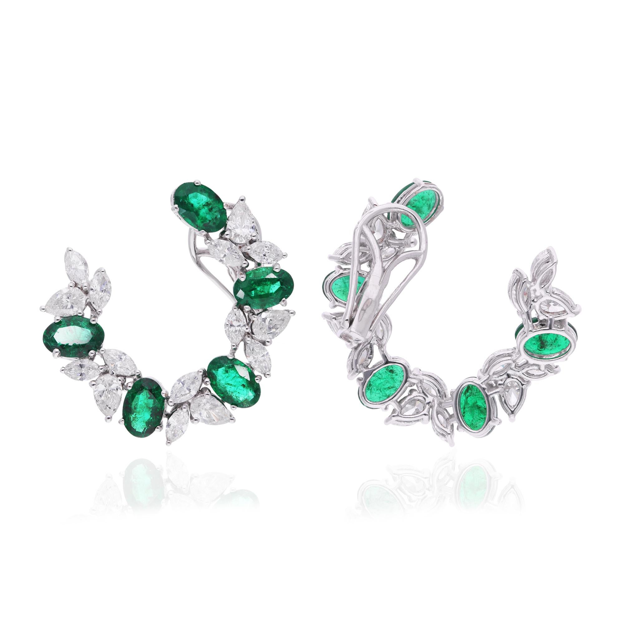 The oval-shaped emerald gemstones take center stage, radiating with vibrant color and brilliance. They are elegantly complemented by sparkling diamonds, meticulously set along the hoops to enhance their allure and add a touch of glamour to the