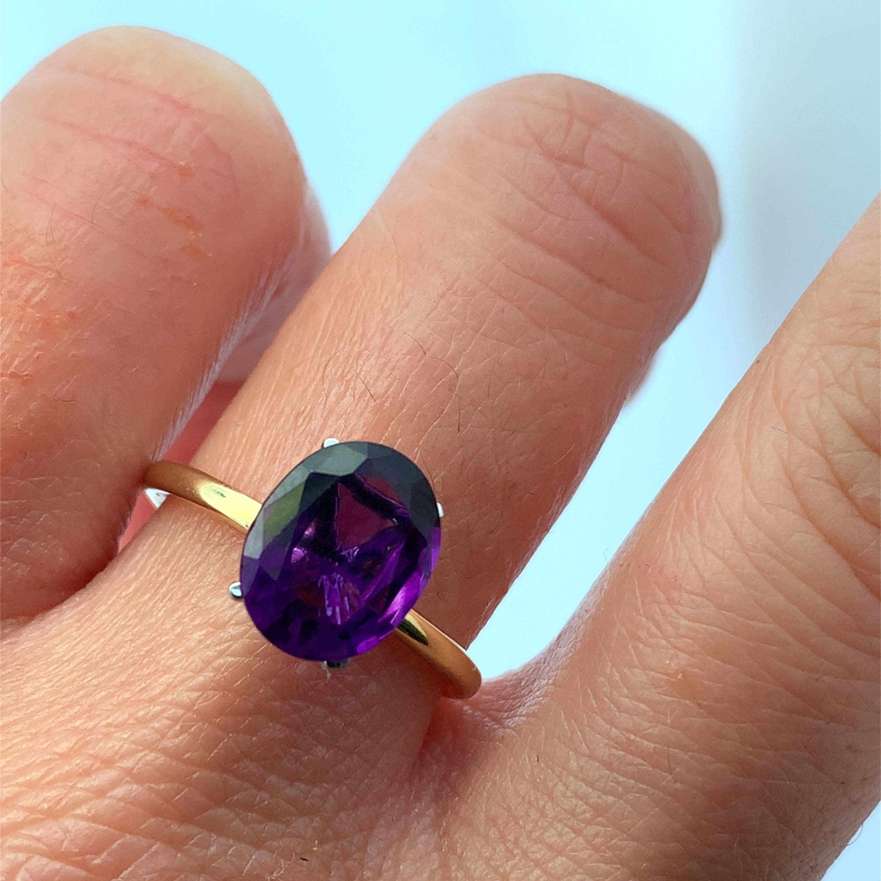 Découvrez l'attrait de cette superbe bague en améthyste magique violette, conçue pour captiver et enchanter. L'améthyste ovale de 2,45ct mesurant environ 10x8mm est magnifiquement sertie dans un élégant bracelet en or 18k, ce qui en fait un
