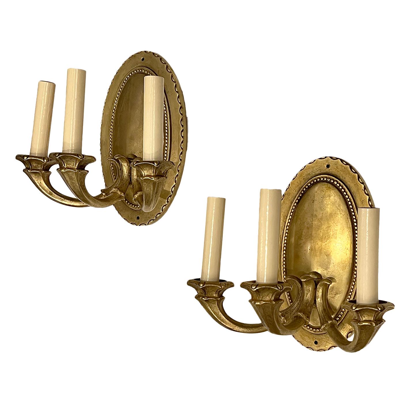 Pair of circa 1940's French oval-shaped neoclassic style  3-light sconces with gilt finish and beading detail on back plate.

Measurements:
Height: 10