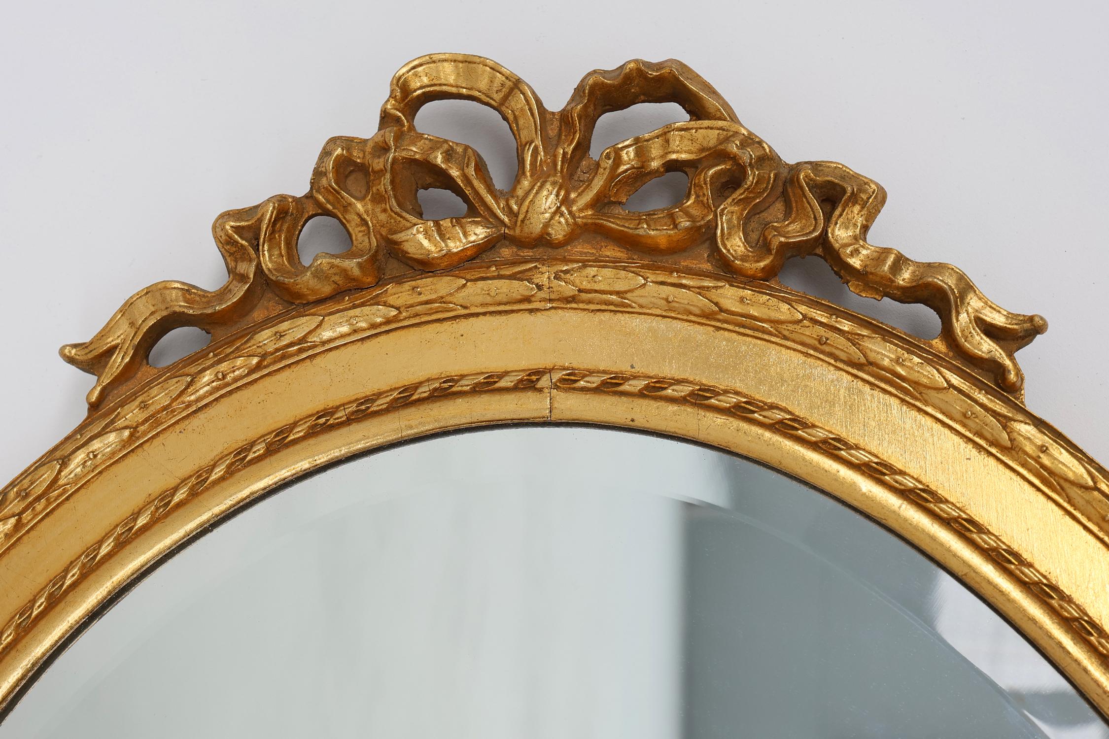 Belgium / 1960 / Mirror / wood / Baroque / Mid-century / Vintage

Traditionally carved and gilded baroque style oval wall mirror. Richly decorated with rows of motifs in the frame and a ribbon bow on top. This mirror has a richly patinated golden