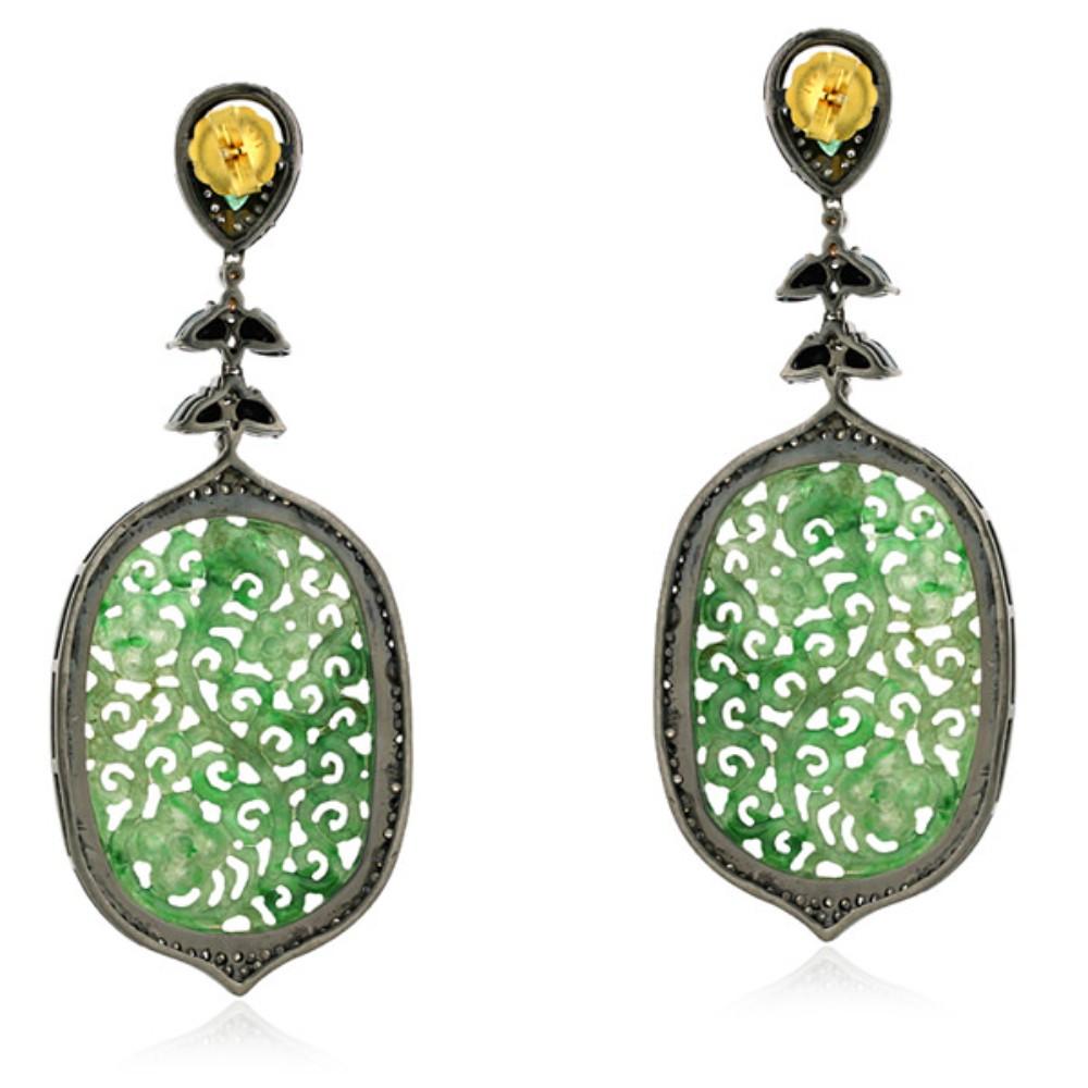 Gorgeous oval-shaped carved jade dangle earrings with emerald and spinel accents and shimmering diamonds. 

18k:1.71g,
Diamond:3.5ct,
Silver:20.65gm,
Emerald:0.7ct,
Jade-41.85,
Spinel-4.10
Size: 90X36MM