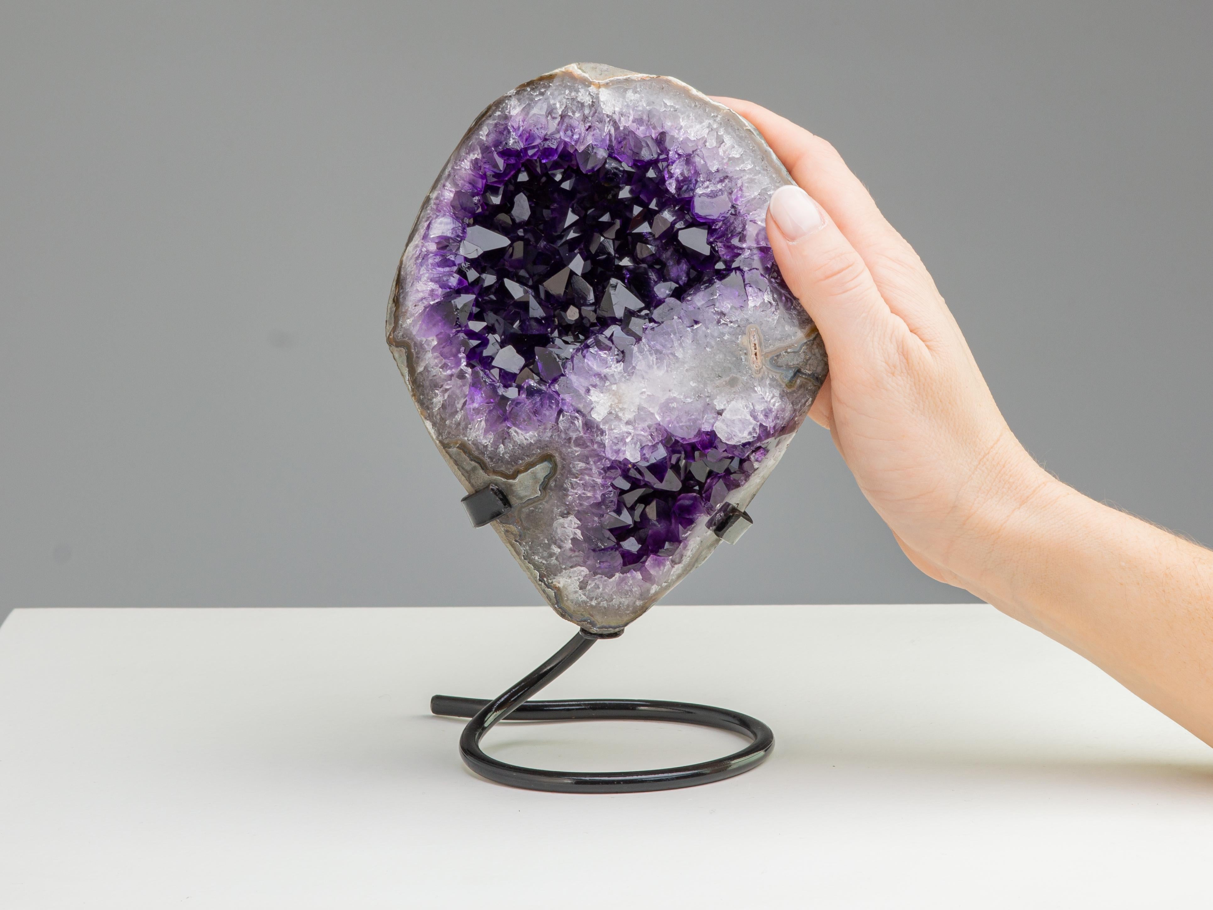 This small oval shaped formation has particularly deep purple, large amethyst crystals separated by a streak of white quartz, exposed from a tangentially cut and polished stalactite.

This piece was legally and ethically sourced directly in the