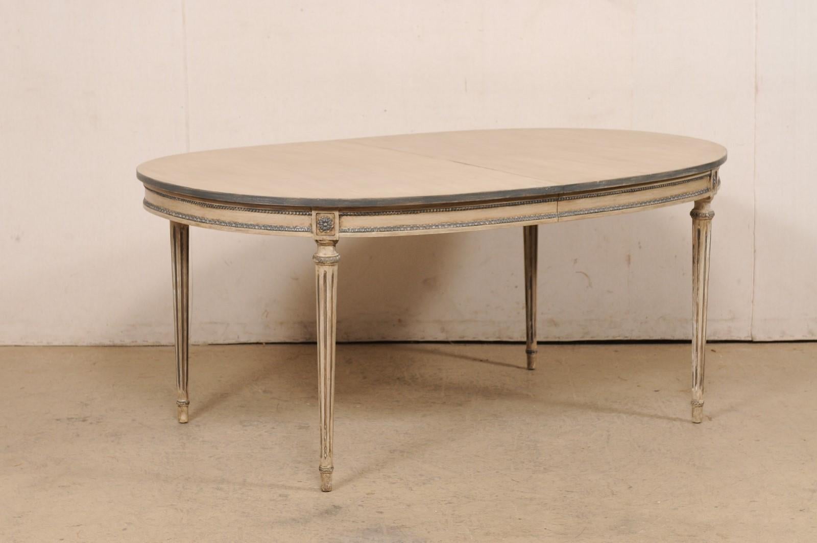 An American oval shaped carved and painted wood dining table from the late 20th century. This vintage table from American furniture makers Kindel Furniture (Grand Rapids, MI) is oval-shaped and has been designed with French inspiration with the