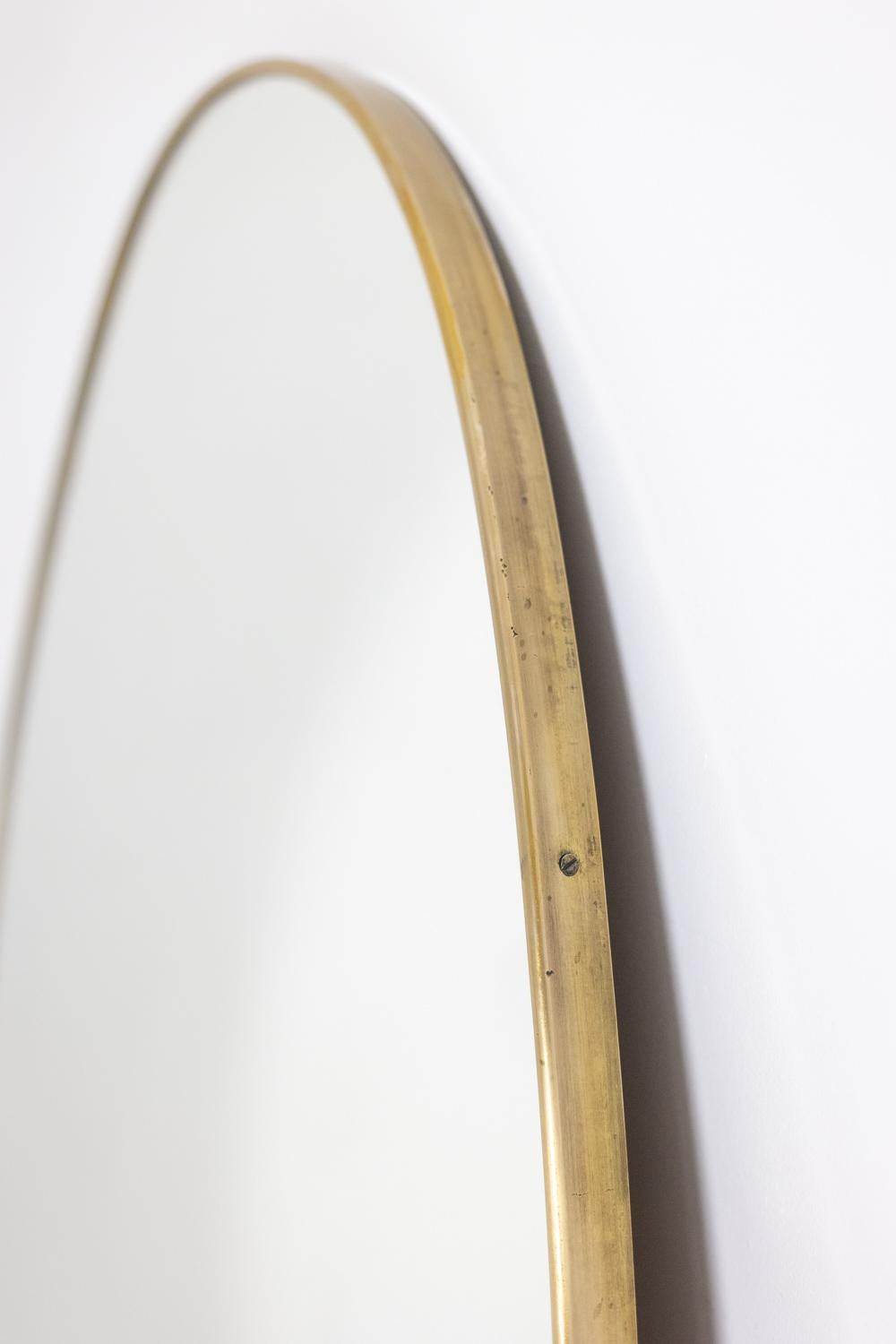 Italian Oval-shaped mirror set with a gilded brass. 1970s.