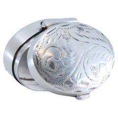 Oval shaped silver pill box with engraving on the hinged lid